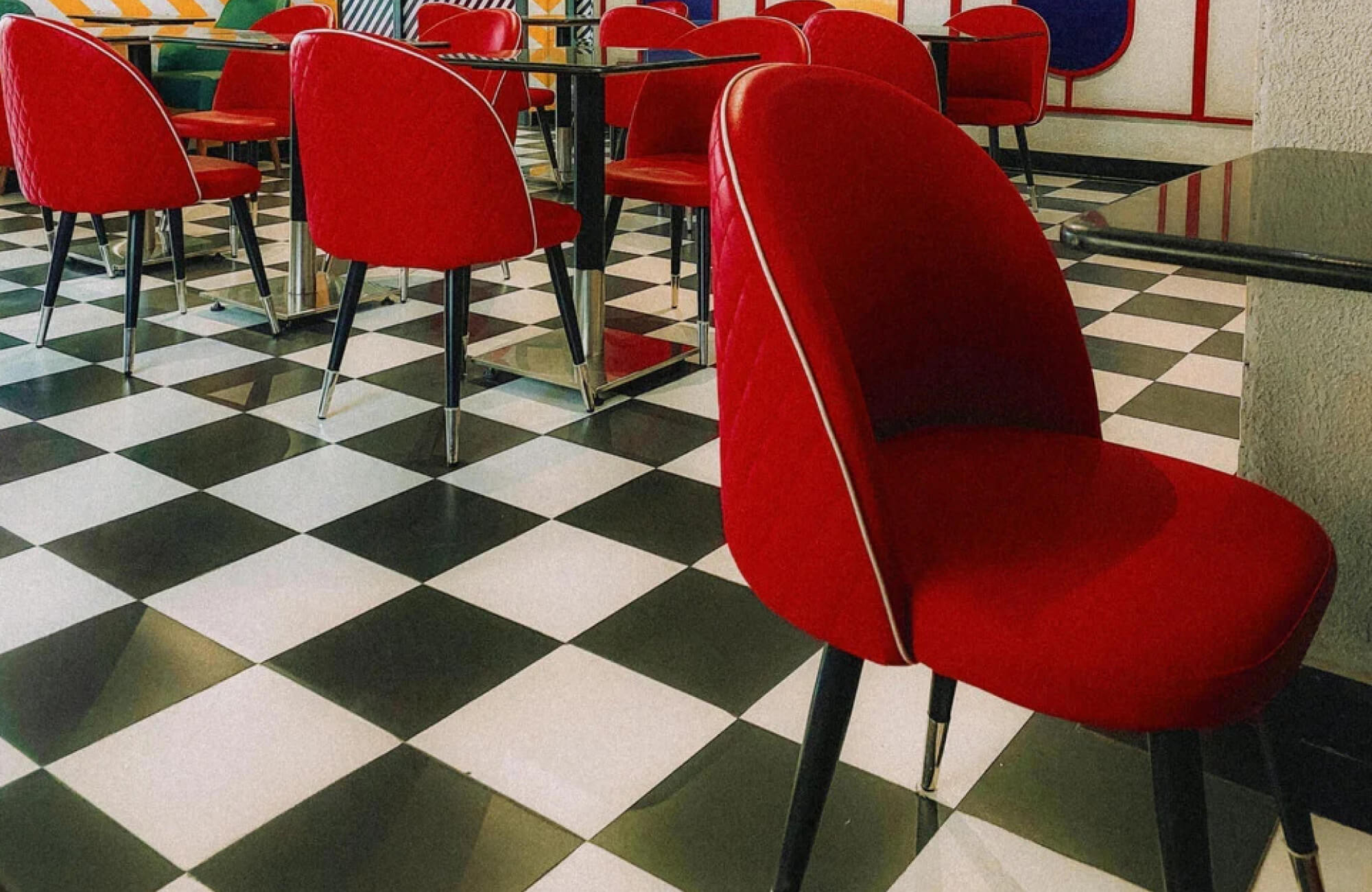 null Retro-style diner with a classic black and white checkered floor and vibrant red chairs for a nostalgic, vintage ambiance.