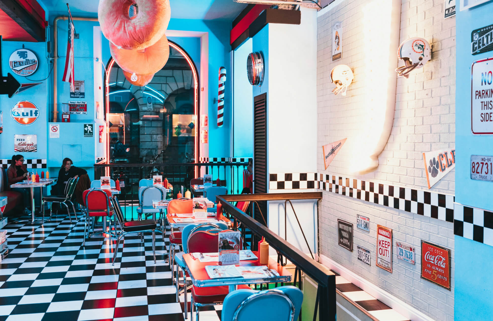 null Retro diner with a black and white checkered floor, pastel blue walls, neon accents, and vintage décor, evoking a classic 1950s ambiance.