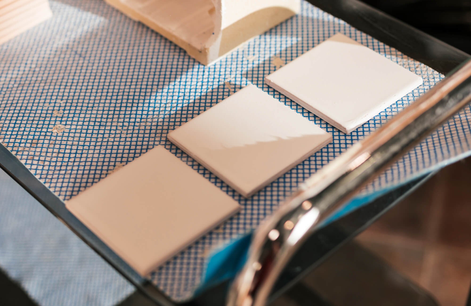 Glossy white tile samples tested with warm-toned grout, ideal for previewing real-life lighting shifts before you commit.