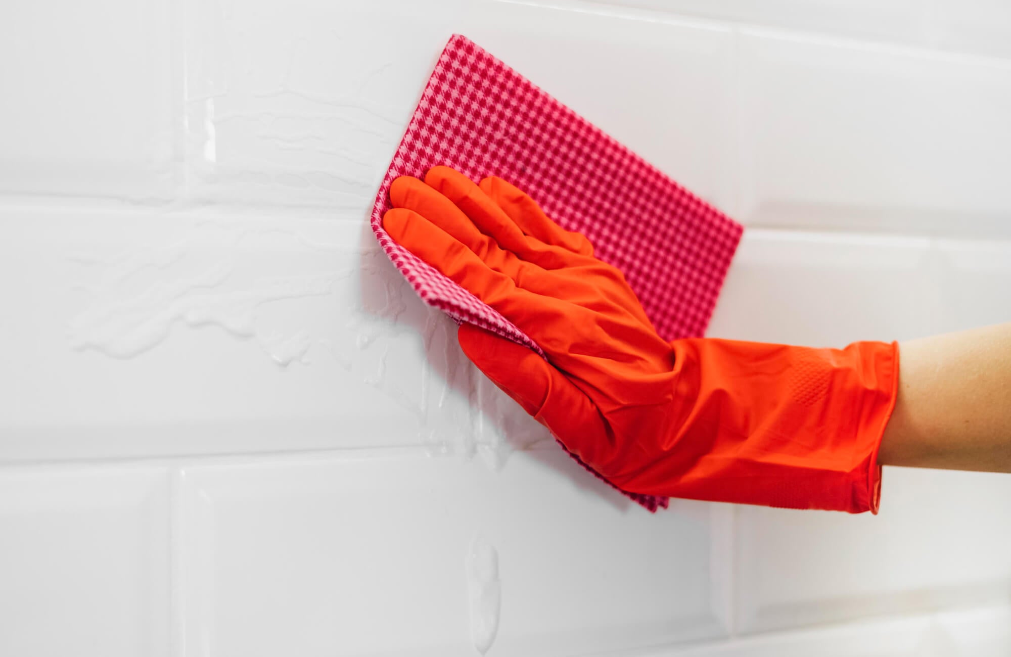 A close-up of glossy white subway tiles and white grout being cleaned, showing how maintenance matters in high-use areas.