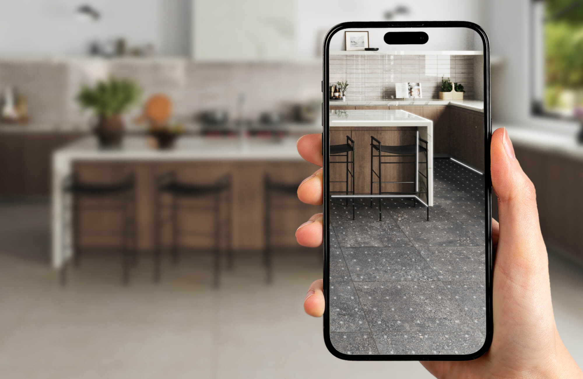 null Hand holding a smartphone in a modern kitchen, displaying an augmented reality view with a different tile floor overlay beneath the kitchen island.