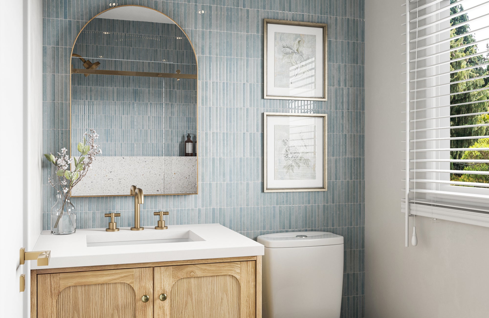 null Arched brass mirror centered above a compact wood vanity with soft blue vertical tiles and natural daylight