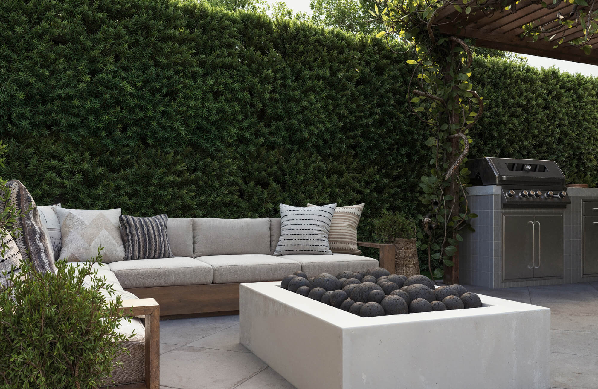 Outdoor seating area with sofa and patterned decorative pillows, arranged for visual balance and comfort beside a modern fire pit setup.