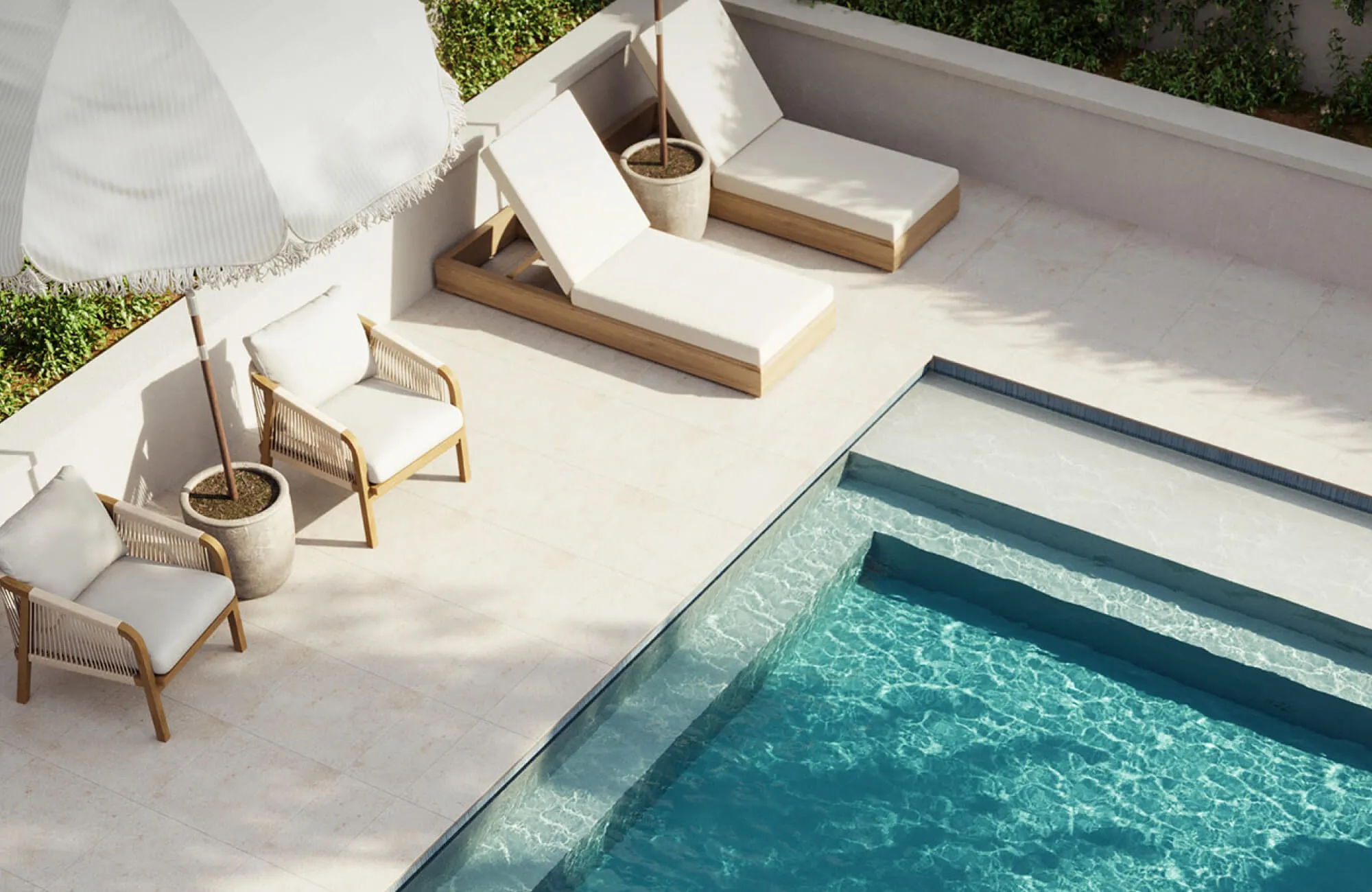 Light beige poolside loungers and woven accent chairs beside a turquoise rectangular swimming pool with cream stone decking, striped umbrellas, and manicured greenery in a modern backyard