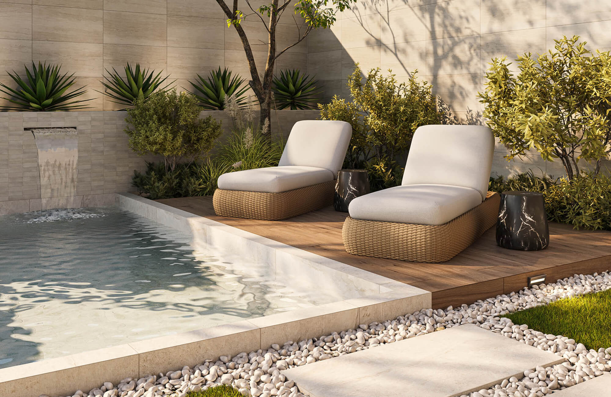 null Warm beige woven chaise loungers with black marble-look side tables on a raised wood pool deck surrounded by natural stone walls, ornamental plants, and mature trees