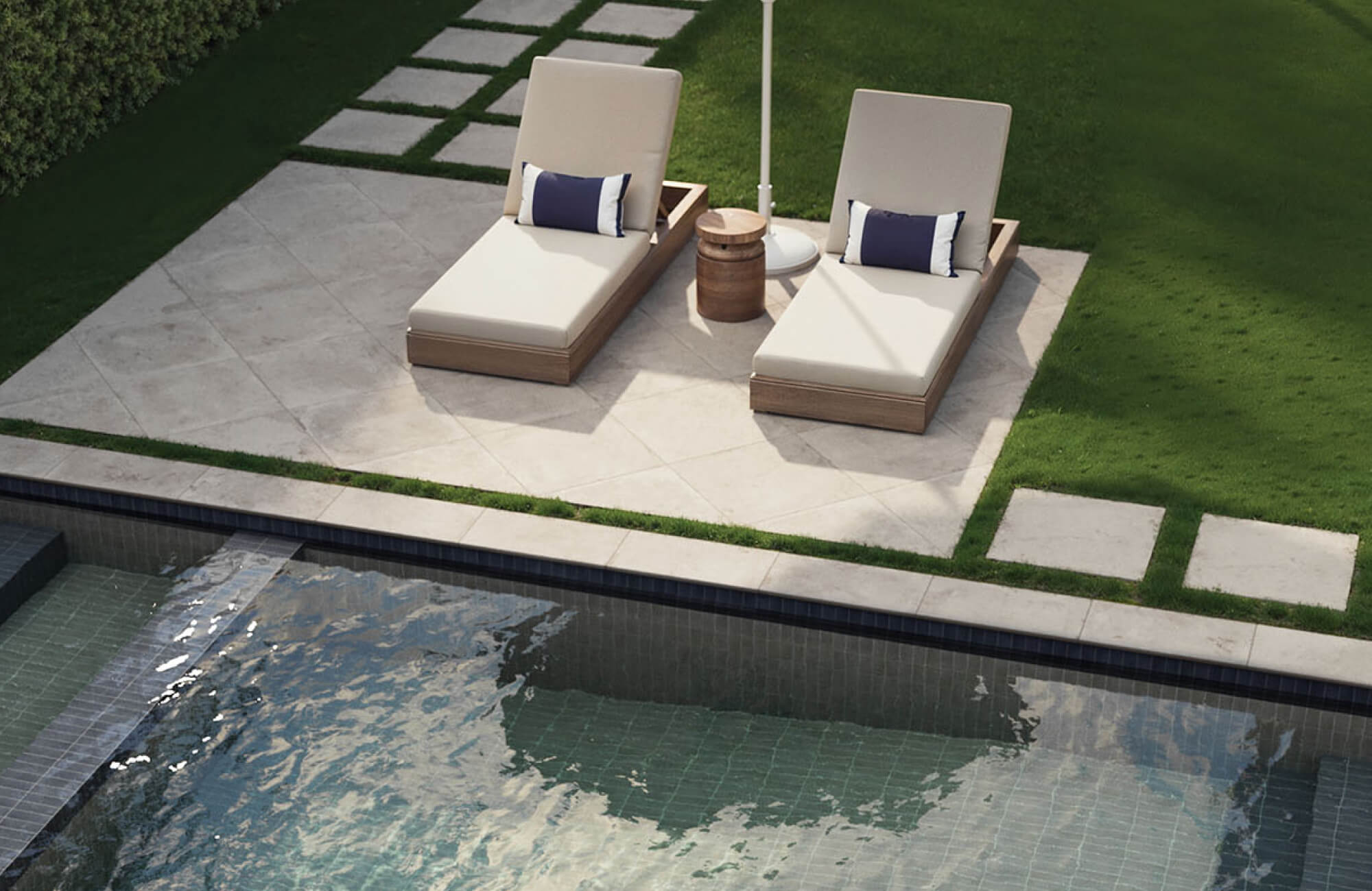 null Neutral cushioned outdoor lounge chairs with warm wood slatted frames arranged on a large cream porcelain pool deck beneath a pergola covered with flowering vines