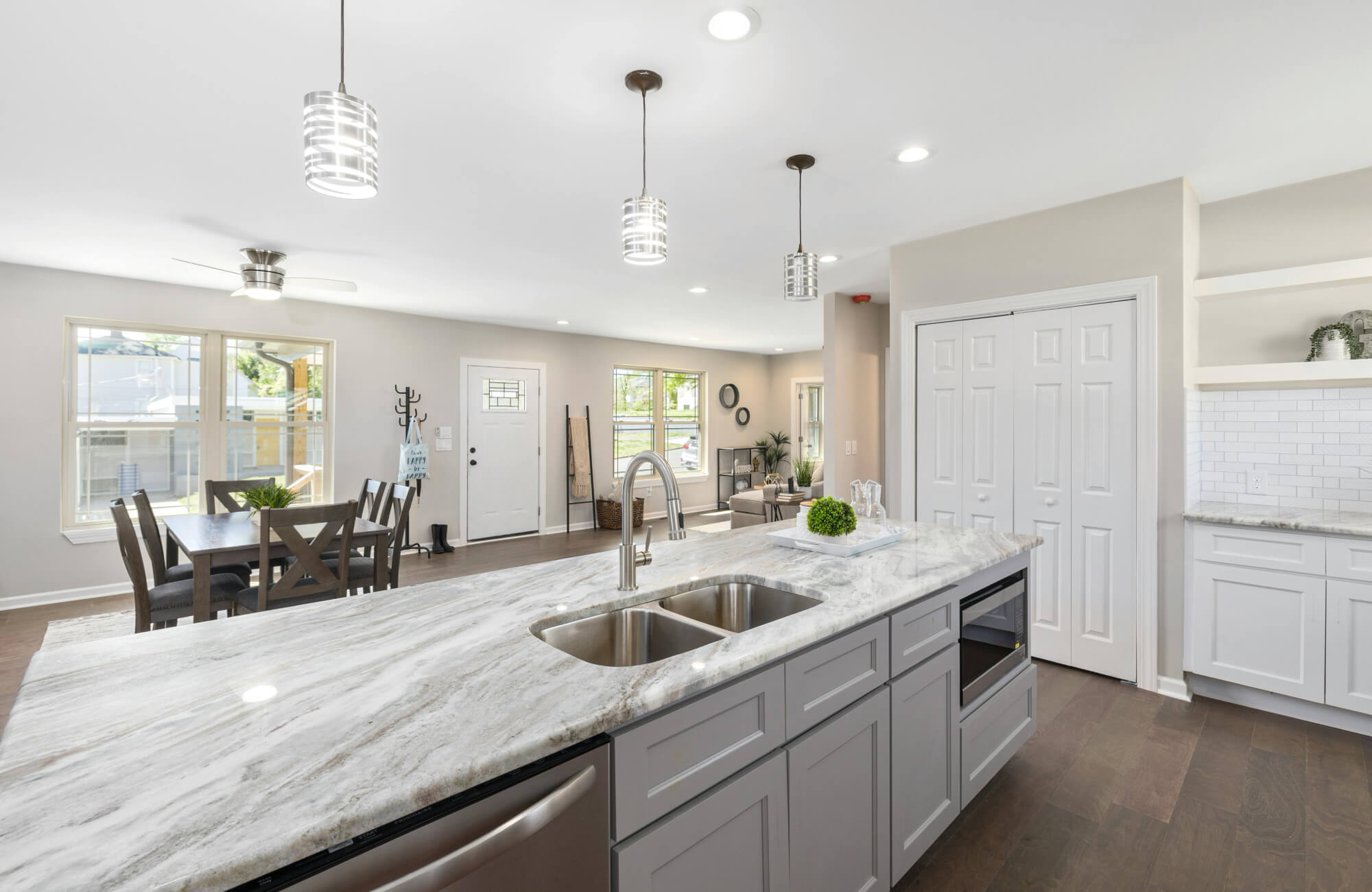 Bright kitchen with a long marble countertop and subtle veining, demonstrating a practical choice for homeowners seeking a clean look with moderate maintenance.