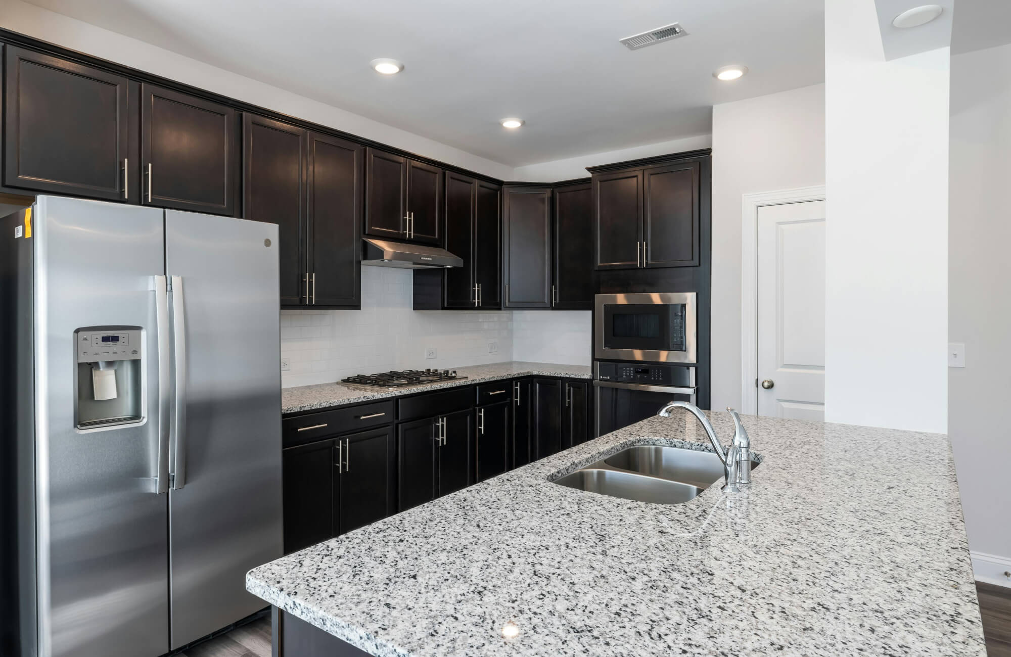 Contemporary kitchen with speckled granite countertop, illustrating a durable alternative often compared when choosing the best marble for kitchen countertops.