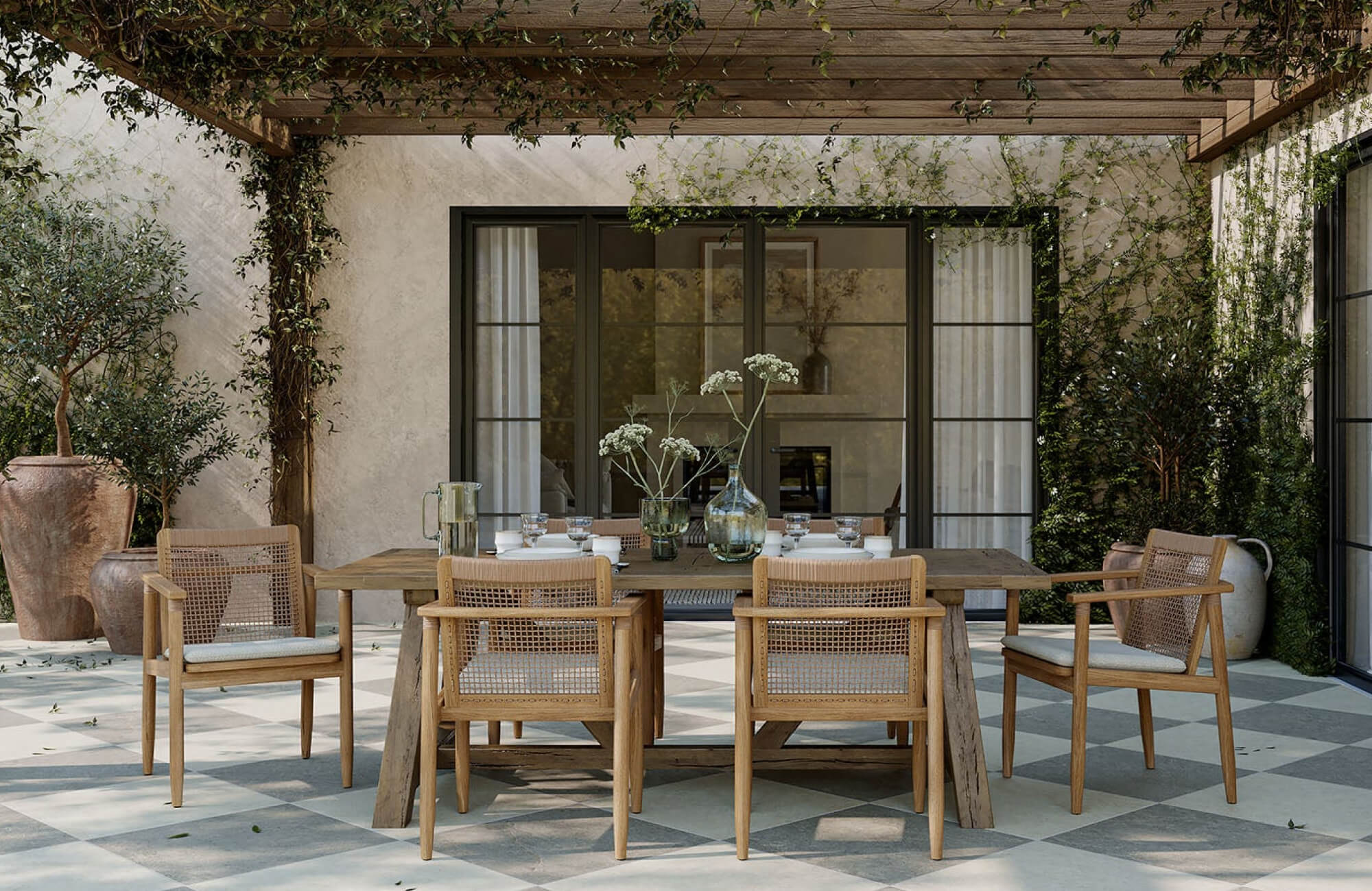null Covered garden patio with a rustic wooden dining table, woven-back chairs, potted plants, and checkerboard floor tiles beneath a wood pergola.
