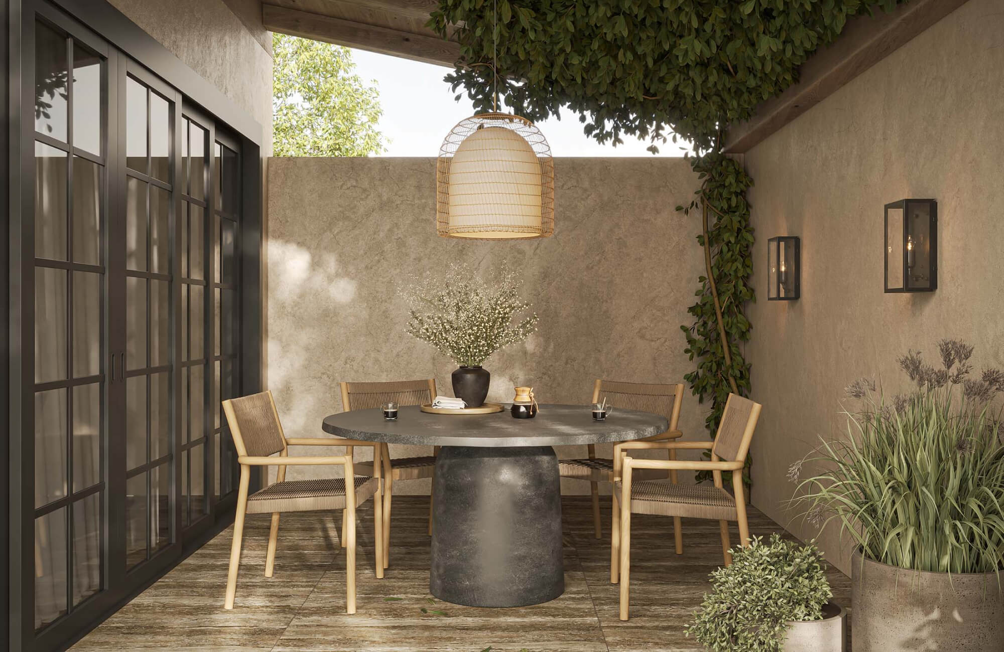 null Shaded patio dining nook with a round stone table, woven wood chairs, wall sconces, greenery, and a hanging pendant light.