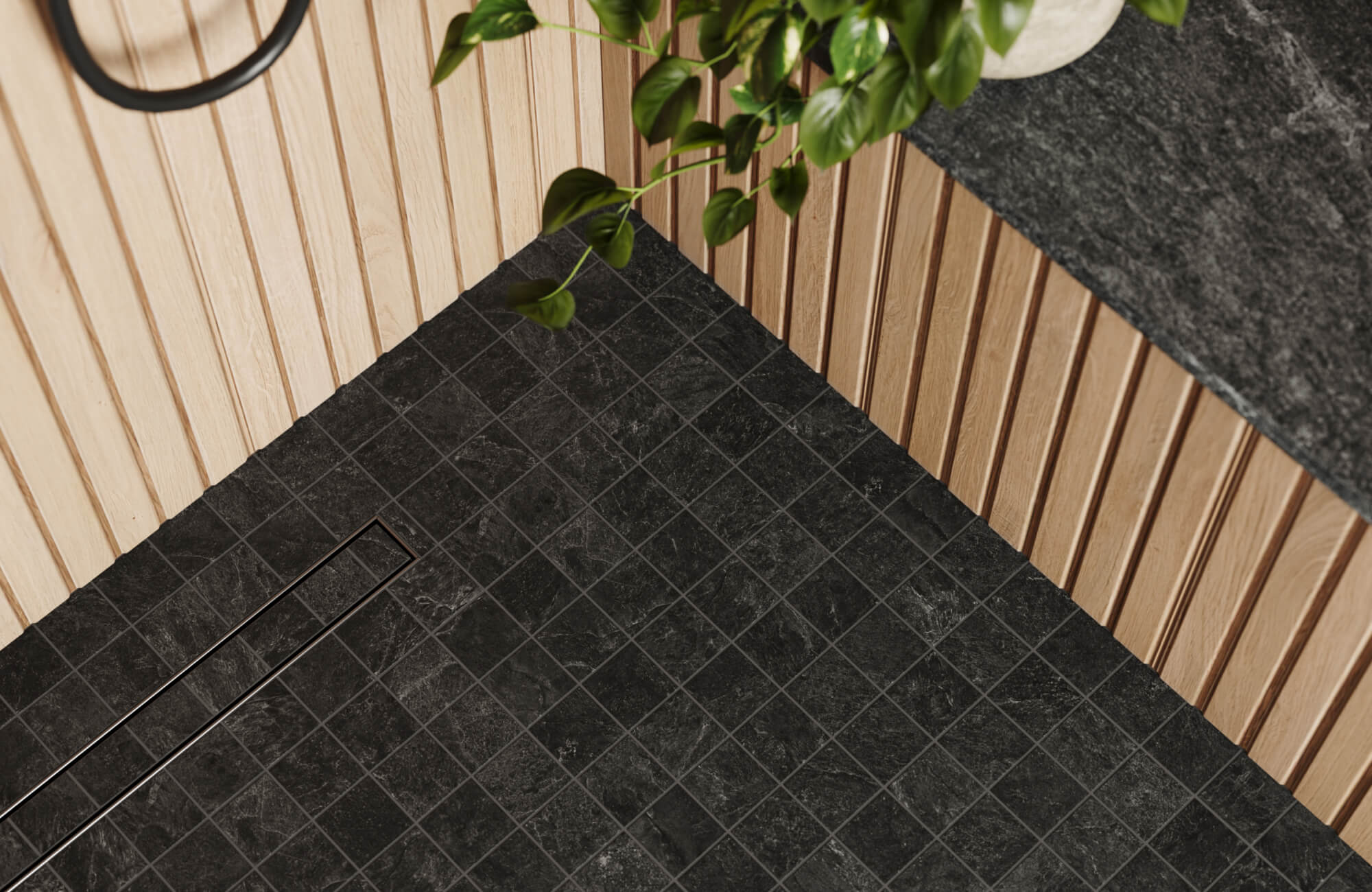 A sleek shower floor with dark textured non-slip tiles, accented by natural wood paneling and a black stone countertop for a modern, earthy aesthetic.