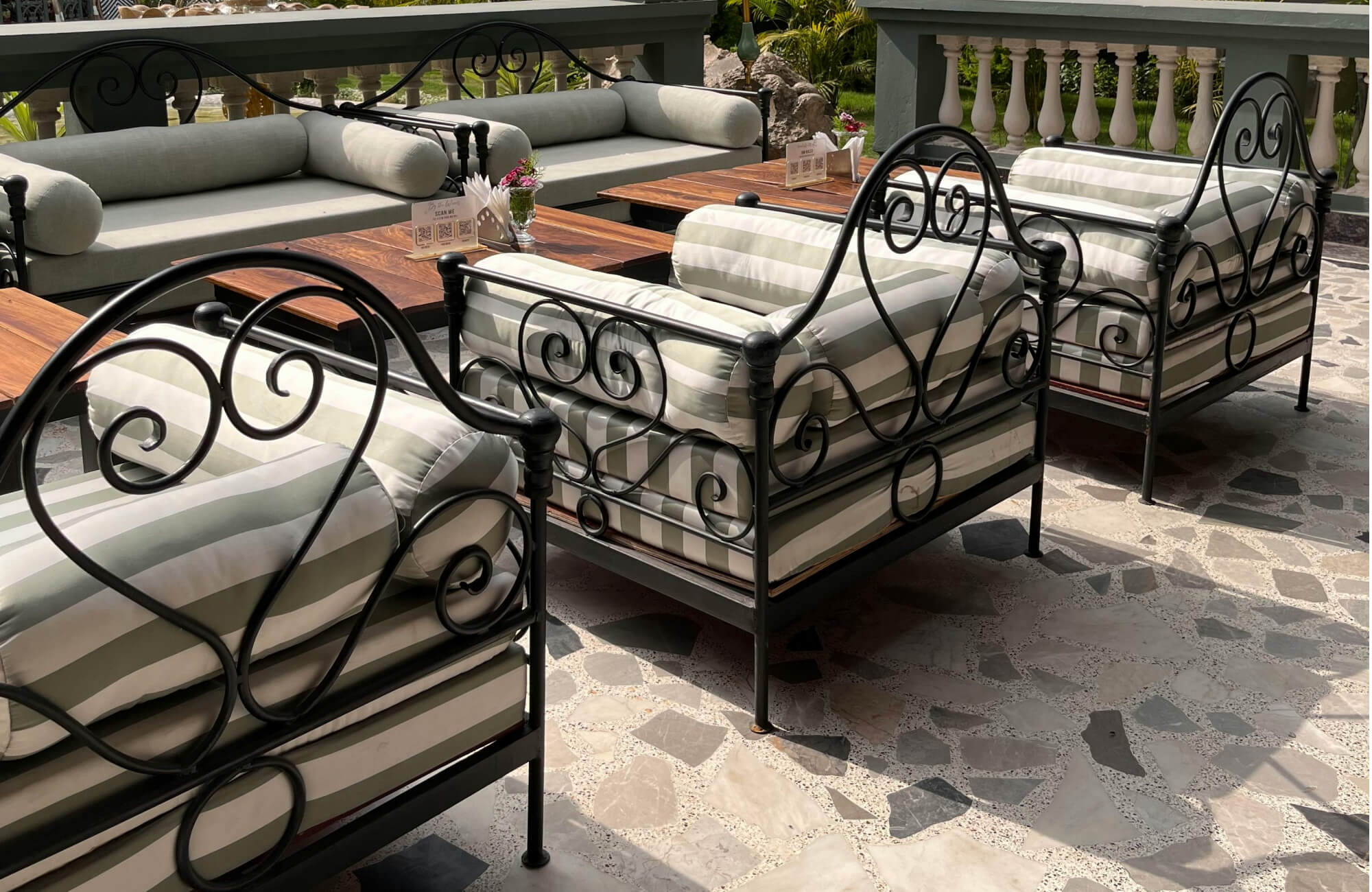 null Charming outdoor patio seating area set on natural stone mosaic outdoor flooring, where irregular stone pieces create a textured, artisanal surface that complements the wrought-iron furniture and relaxed resort-style ambiance.