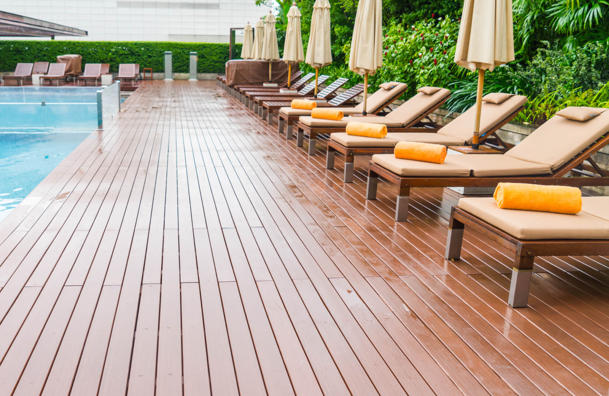 null Resort-style pool deck showcasing slip-resistant wood-look composite decking outdoor flooring, providing a warm, uniform surface that complements the lounge chairs and umbrellas while enhancing durability around the pool area.