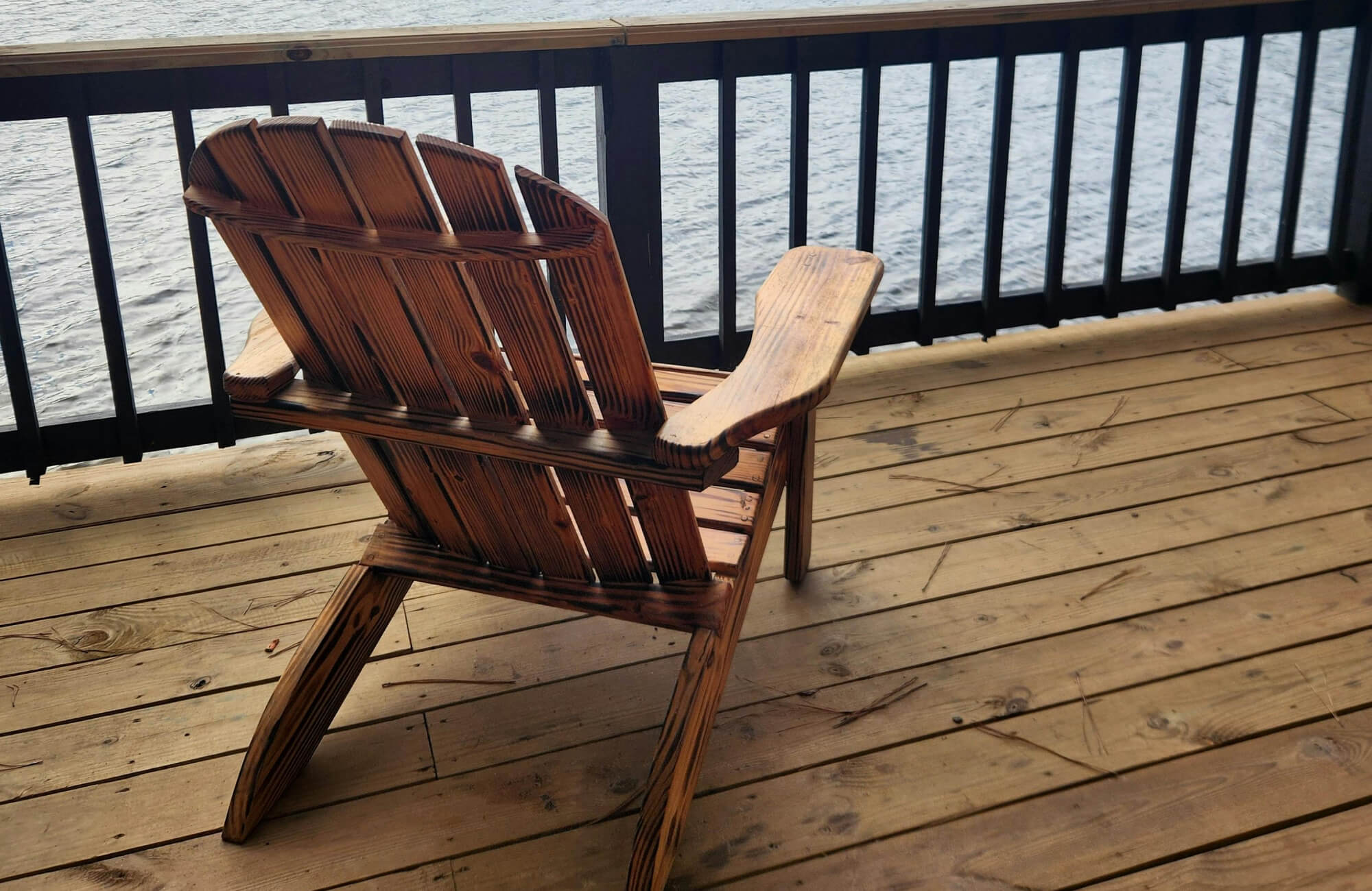 null Cozy lakeside deck featuring natural wood plank outdoor flooring, where warm-toned boards enhance the rustic charm of the Adirondack chair and create a relaxed, waterfront retreat.