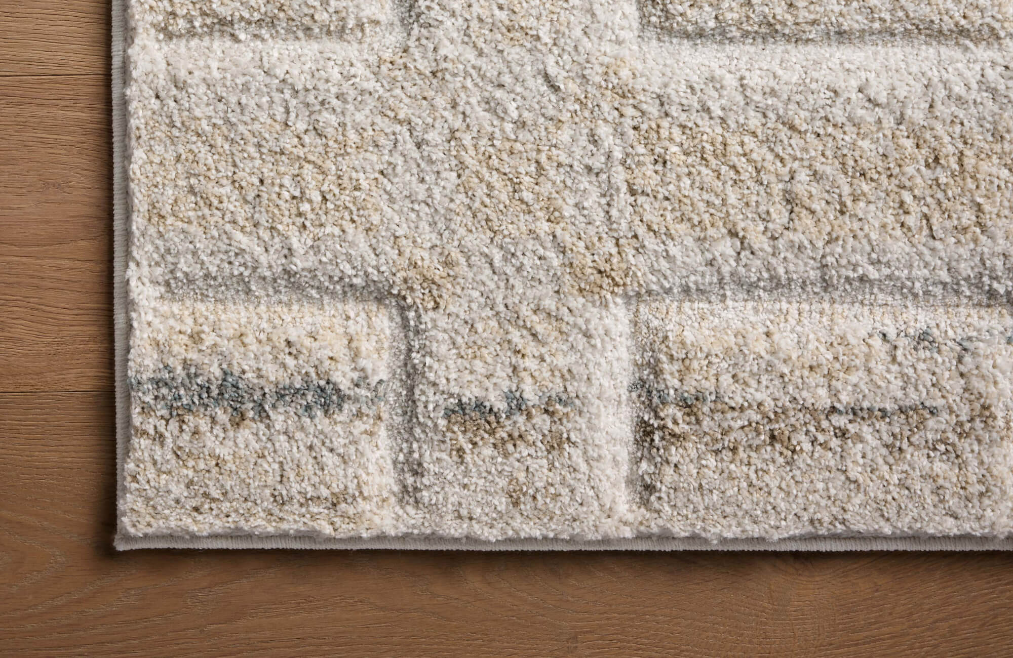null A close-up view of a textured, low-pile rug in neutral tones on hardwood flooring, emphasizing fiber detail and quality.