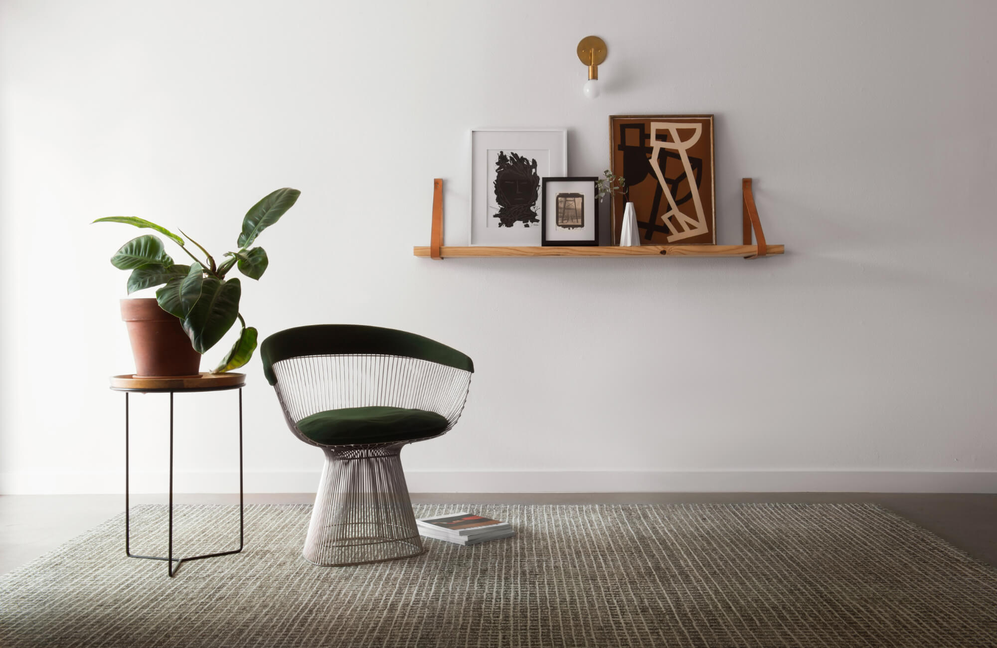 null A minimalist room with a modern chair and plant atop a subtle patterned rug, highlighting clean design and texture.