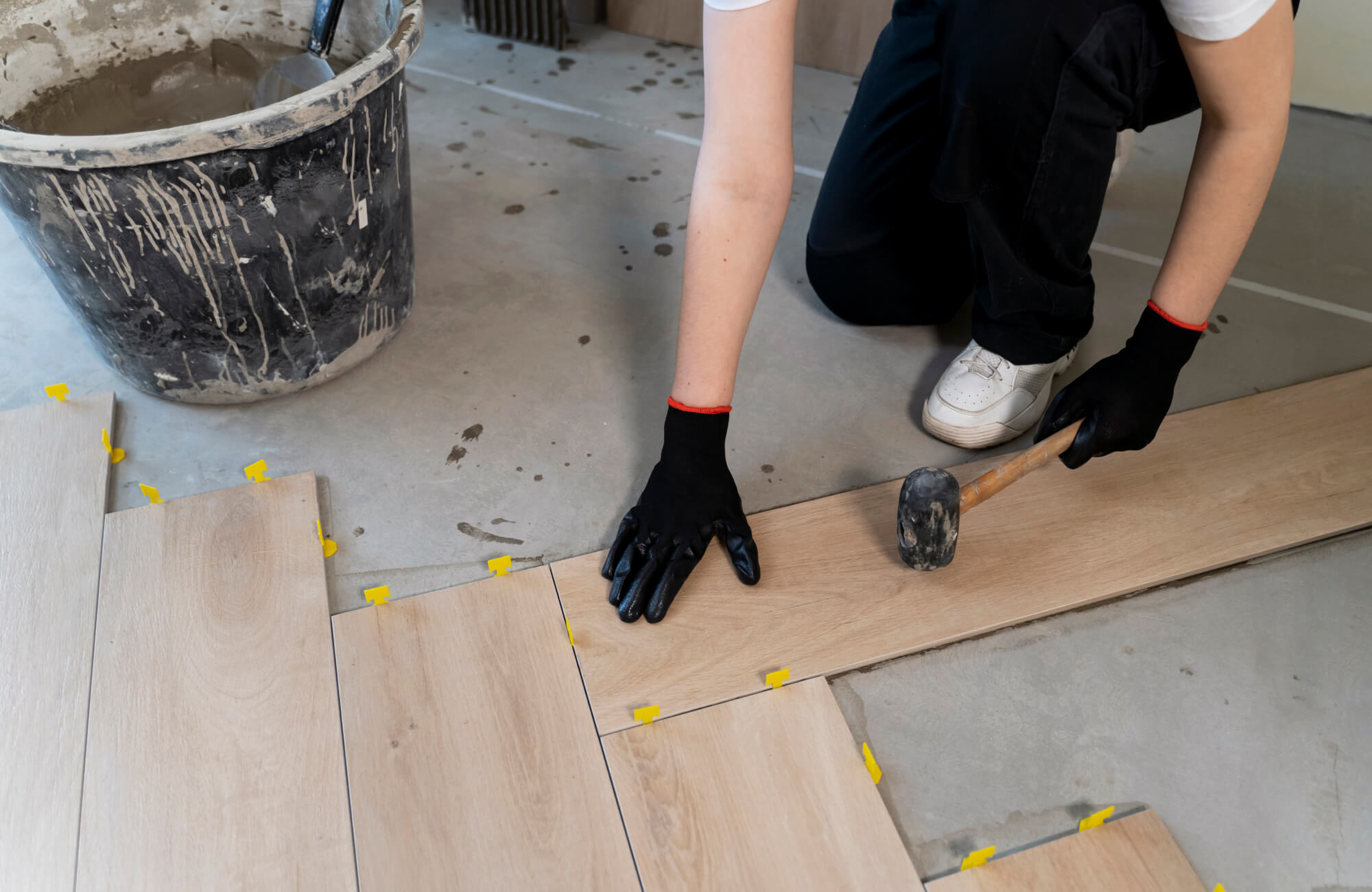 null Installing light wood look tiles with precision using spacers and a rubber mallet for a seamless, professional finish.