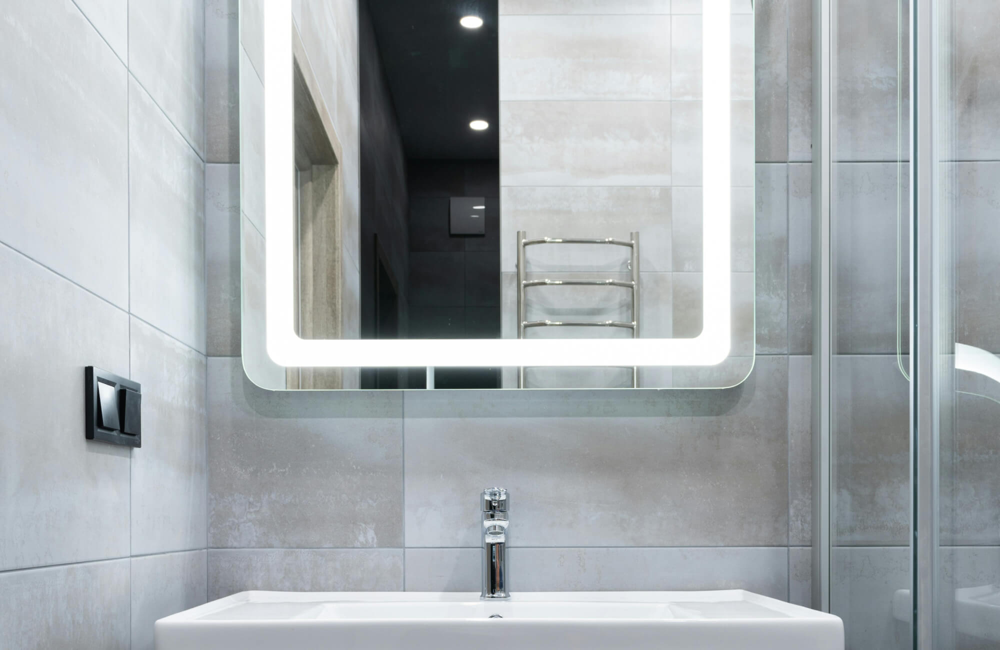 null Square lighted mirror providing crisp forward illumination over a minimalist sink in a gray bathroom.