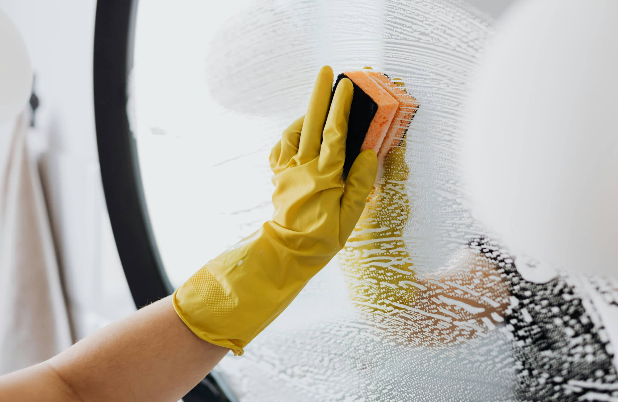 null Hand cleaning a lighted mirror surface with soap and a sponge, showing maintenance of illuminated mirrors.