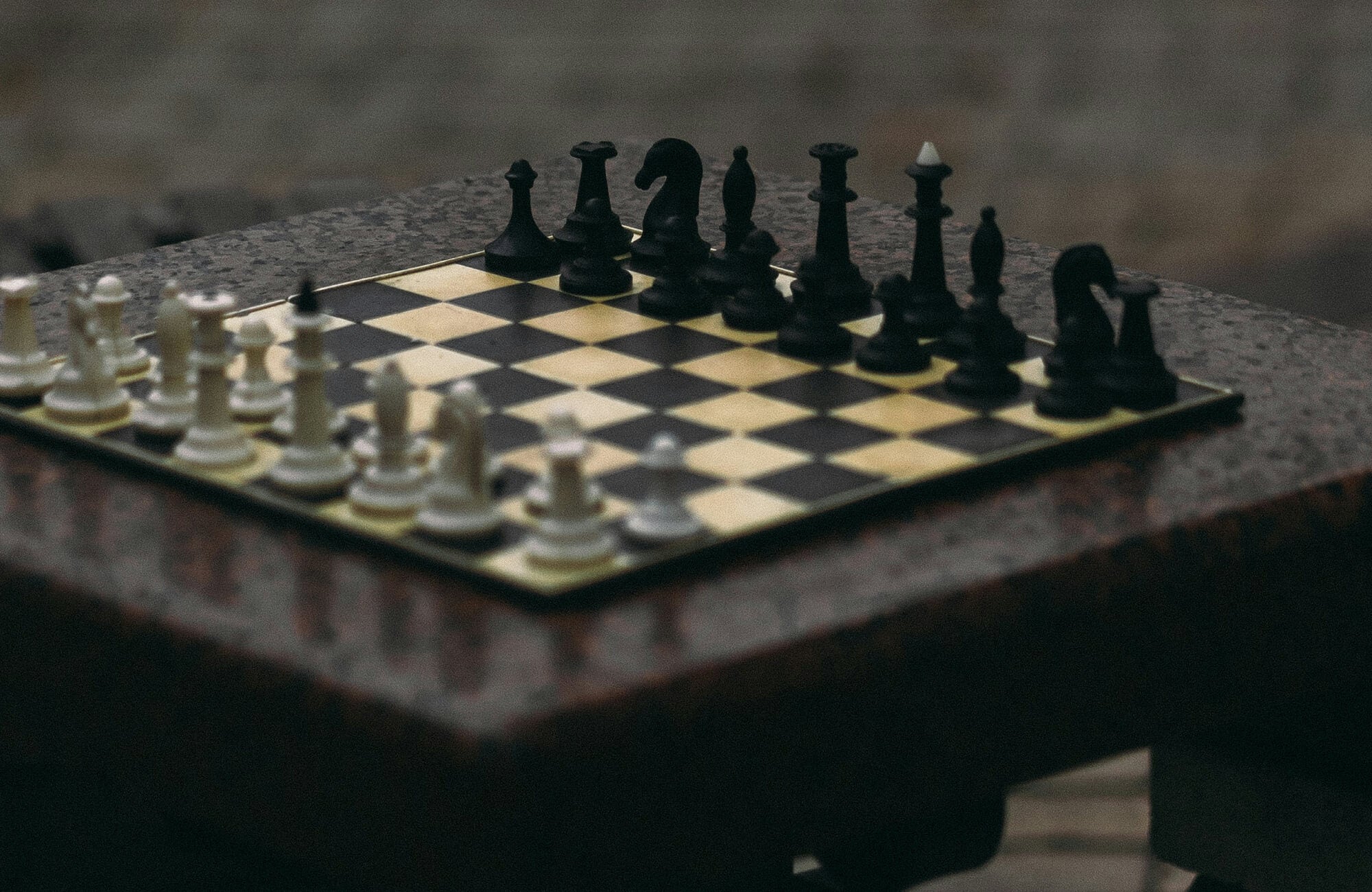 null Outdoor chess board with black and white pieces set up for a game, showcasing a classic checkerboard pattern on a stone table