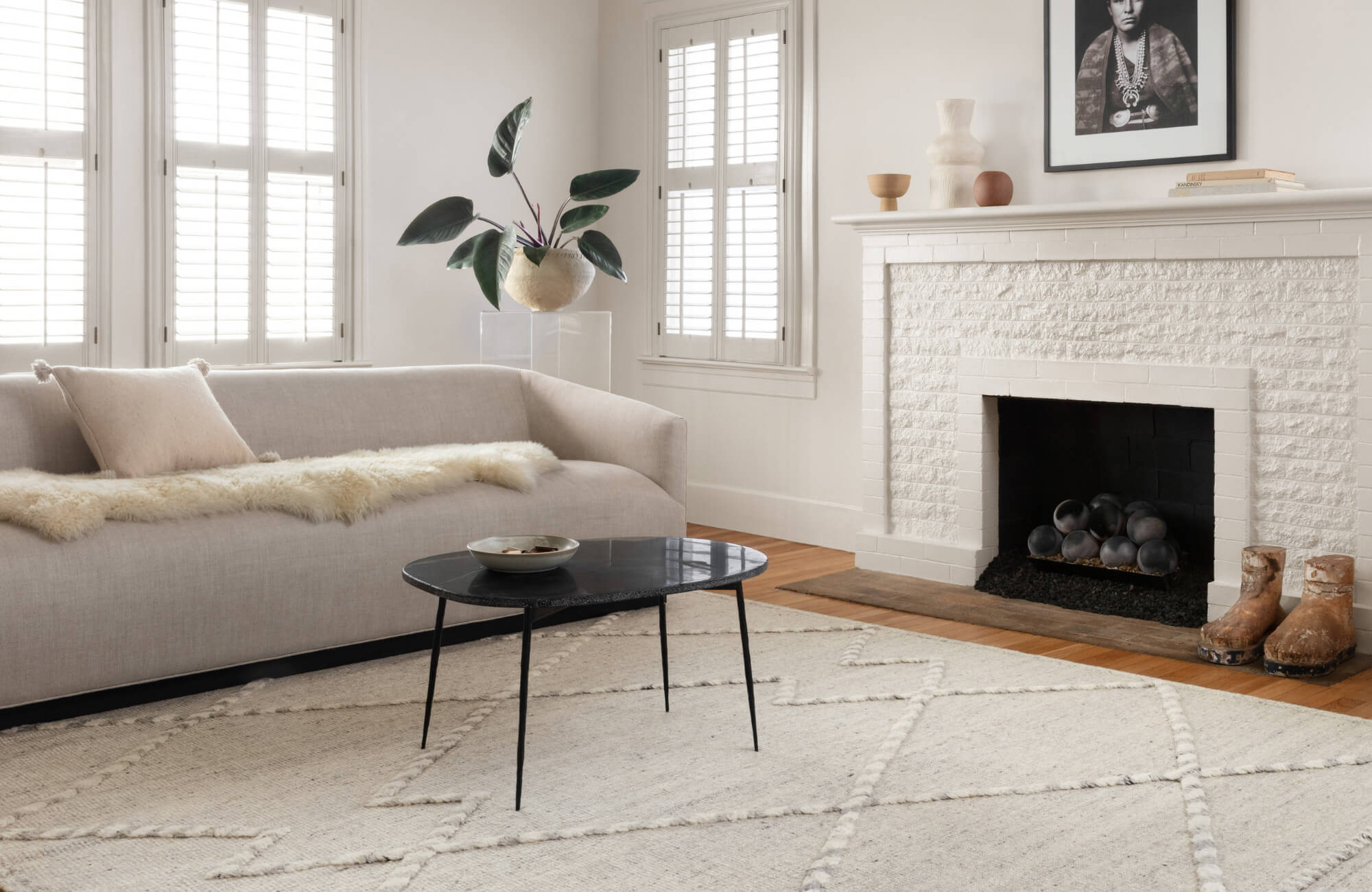 null Bright living room featuring a light patterned rug, neutral sofa, modern décor, and a white brick fireplace with clean, minimal styling.