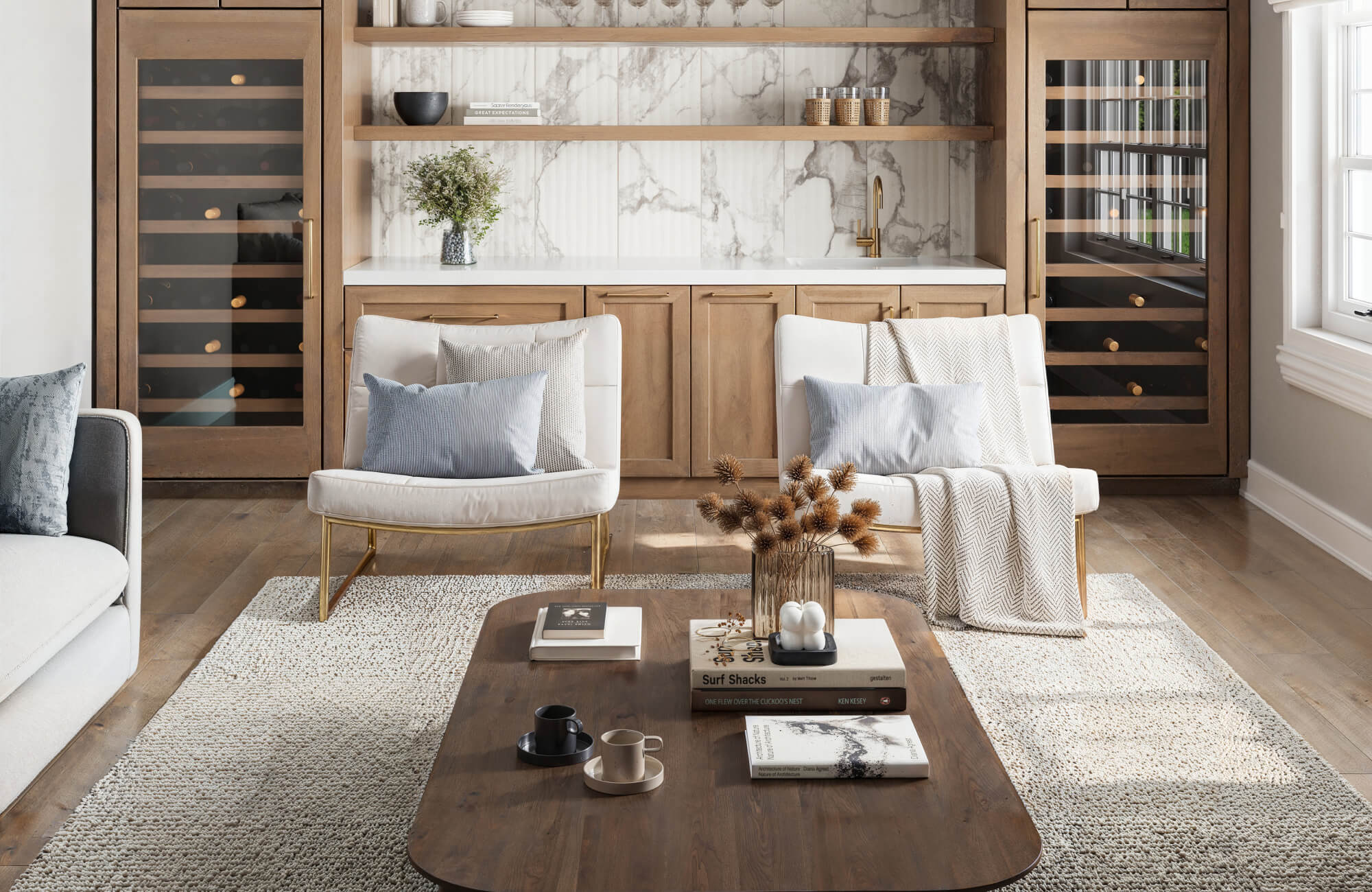 null Large neutral textured area rug under coffee table and accent chairs in modern living room with layered seating and warm wood accents.