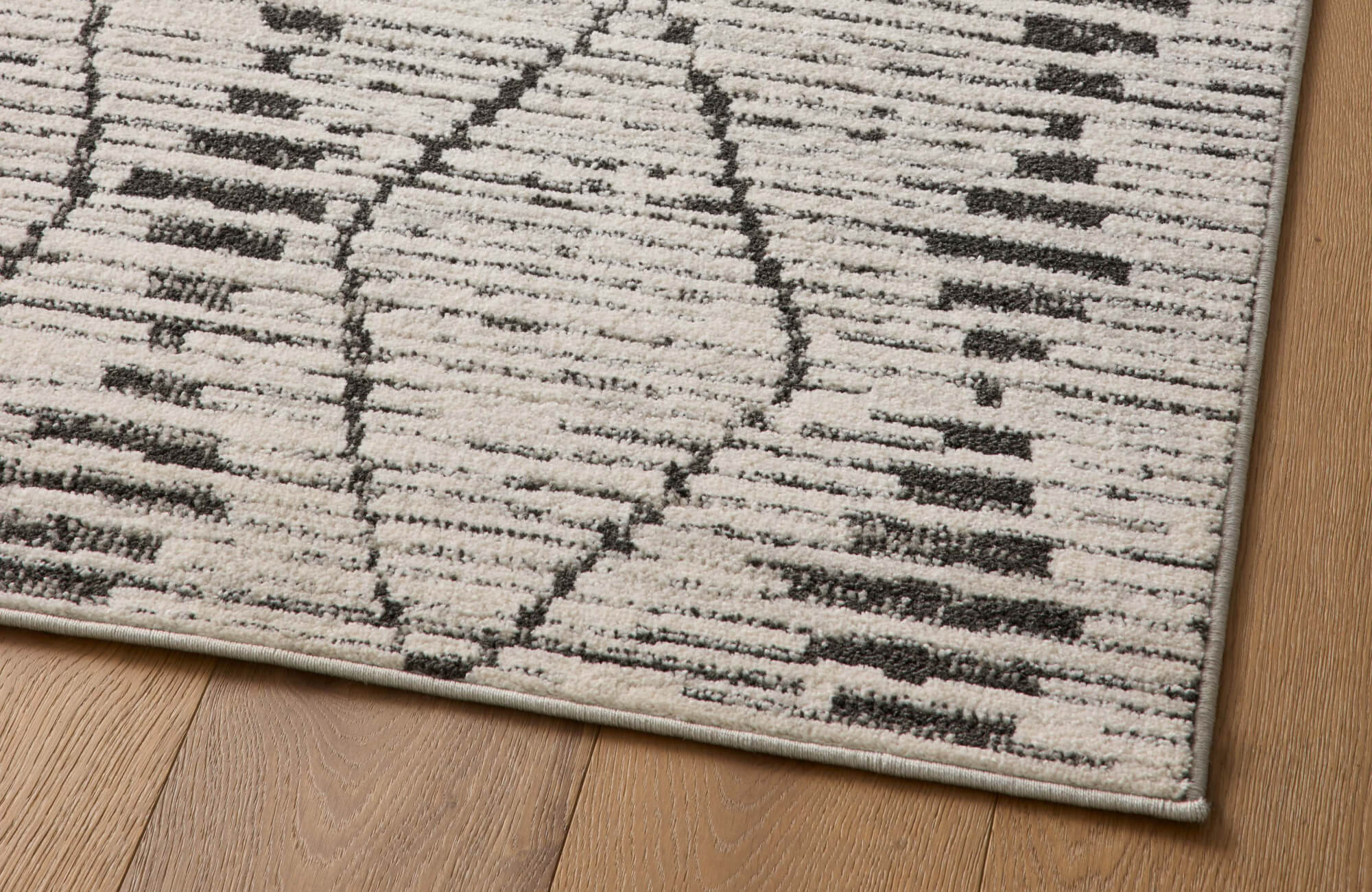 null Neutral textured area rug with modern geometric pattern and low-pile surface detail on wood flooring.