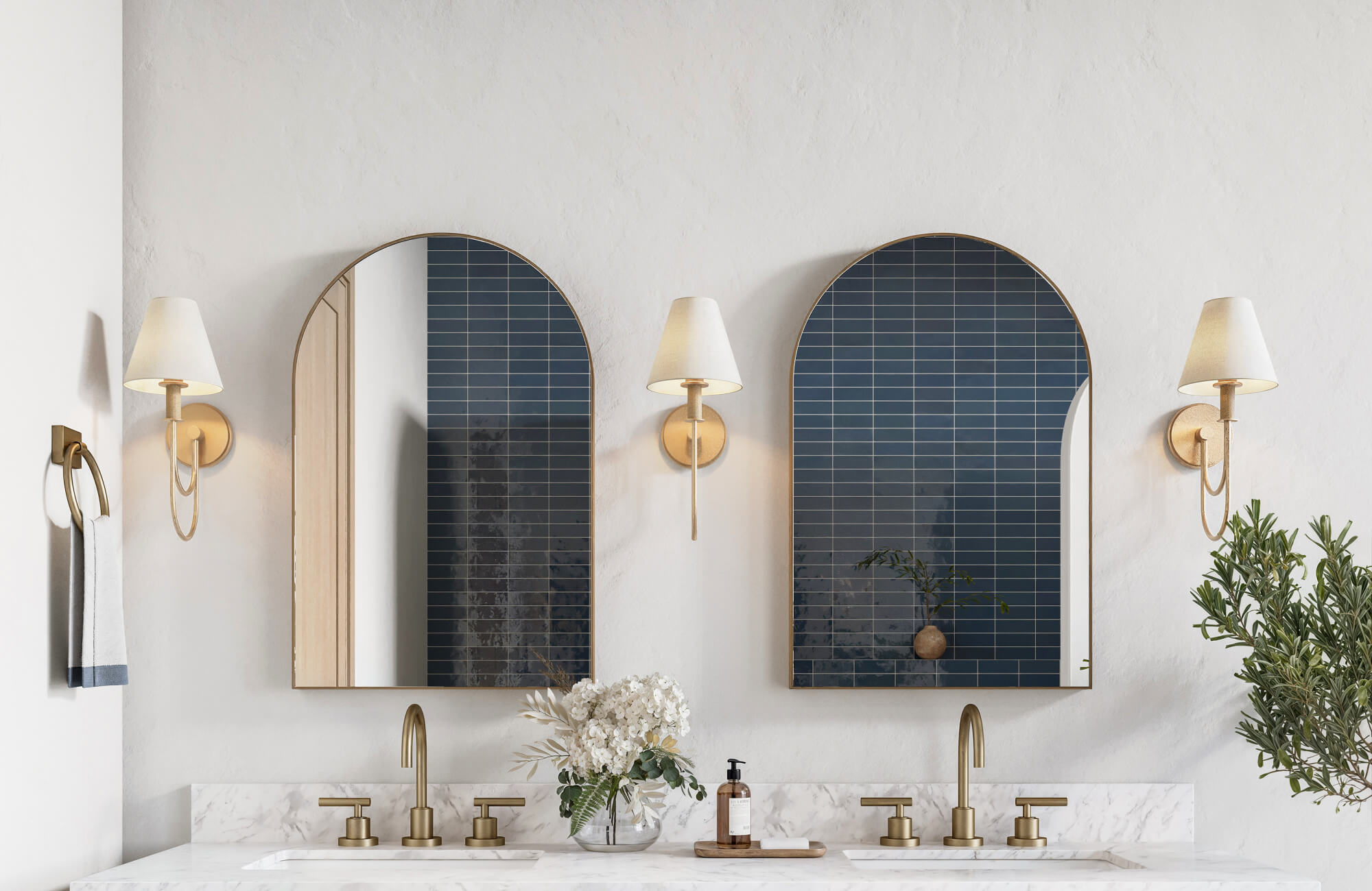null Brass wall sconces and arched mirrors reflect glossy navy tile backsplash above a marble double vanity.