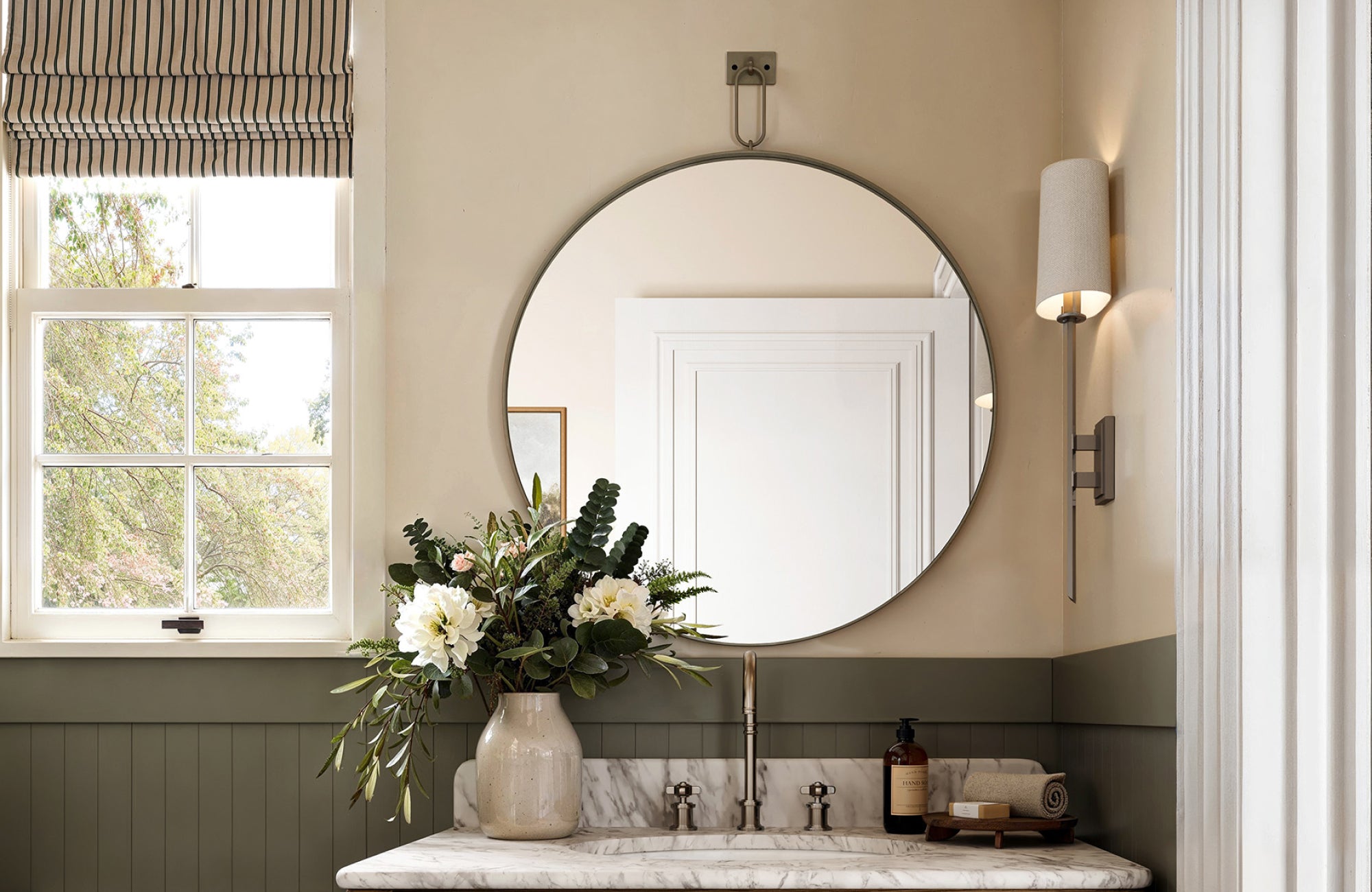 Round mirror hung higher, centered on the wall, with visible space above the faucet for an airy, balanced look.