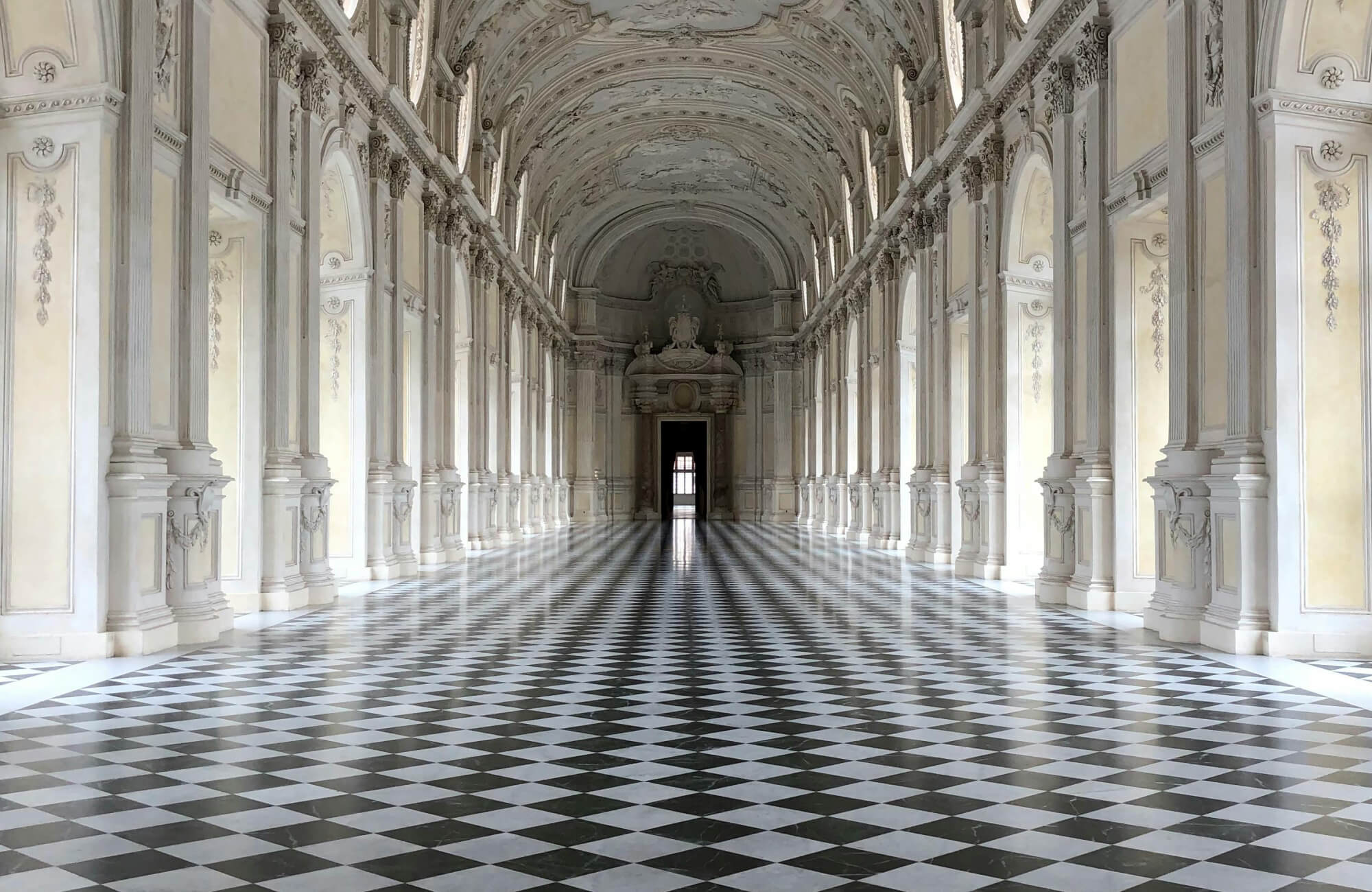 null Grand palace hallway with intricate baroque detailing, soaring arches, and a striking black and white checkered marble floor for timeless elegance.