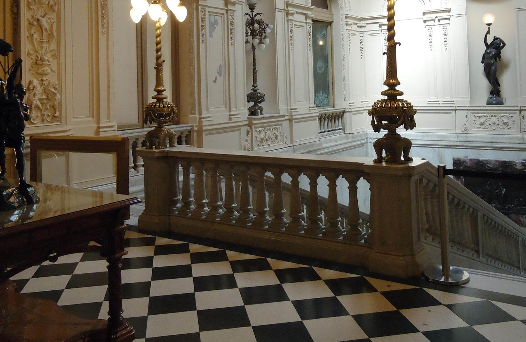 null Opulent interior with black and white checkered flooring, ornate gold fixtures, and intricate architectural details exuding classic elegance.