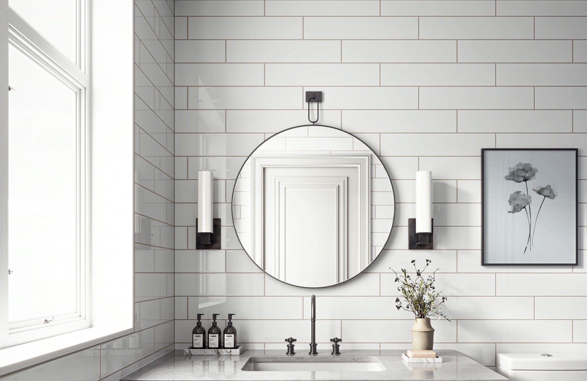 null Vertical wall sconces flank a round mirror in a bright bathroom with glossy subway tile and soft natural light.