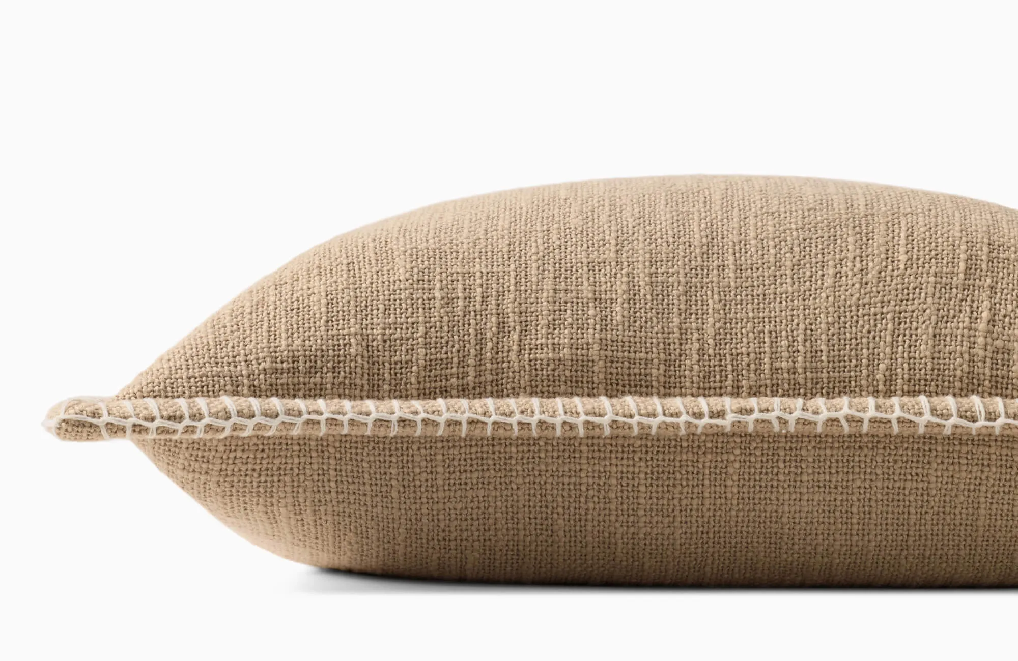 Close-up side view of a full and firm beige woven pillow with white whipstitch edge detail against a clean white background.