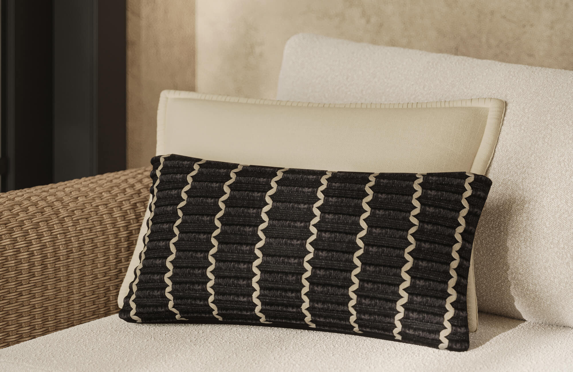 null Close-up of a black textured lumbar pillow with cream wavy lines styled against a white stitched pillow on a cream boucle couch with brown rattan beside it.