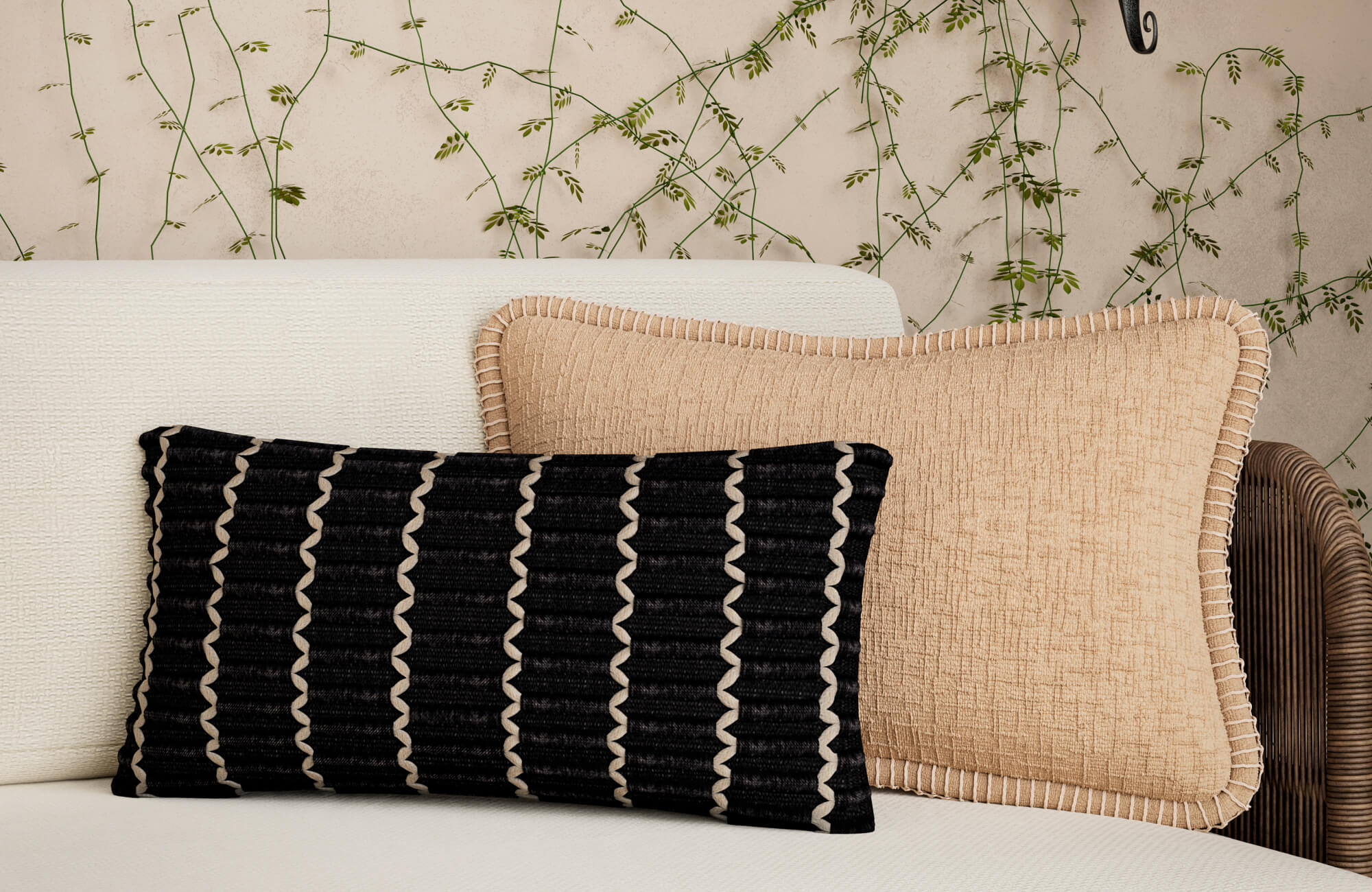 null White sofa styled with a black ribbed lumbar pillow with white wave detail and a full beige linen-look pillow with beige border stitching against a green botanical wallpaper.