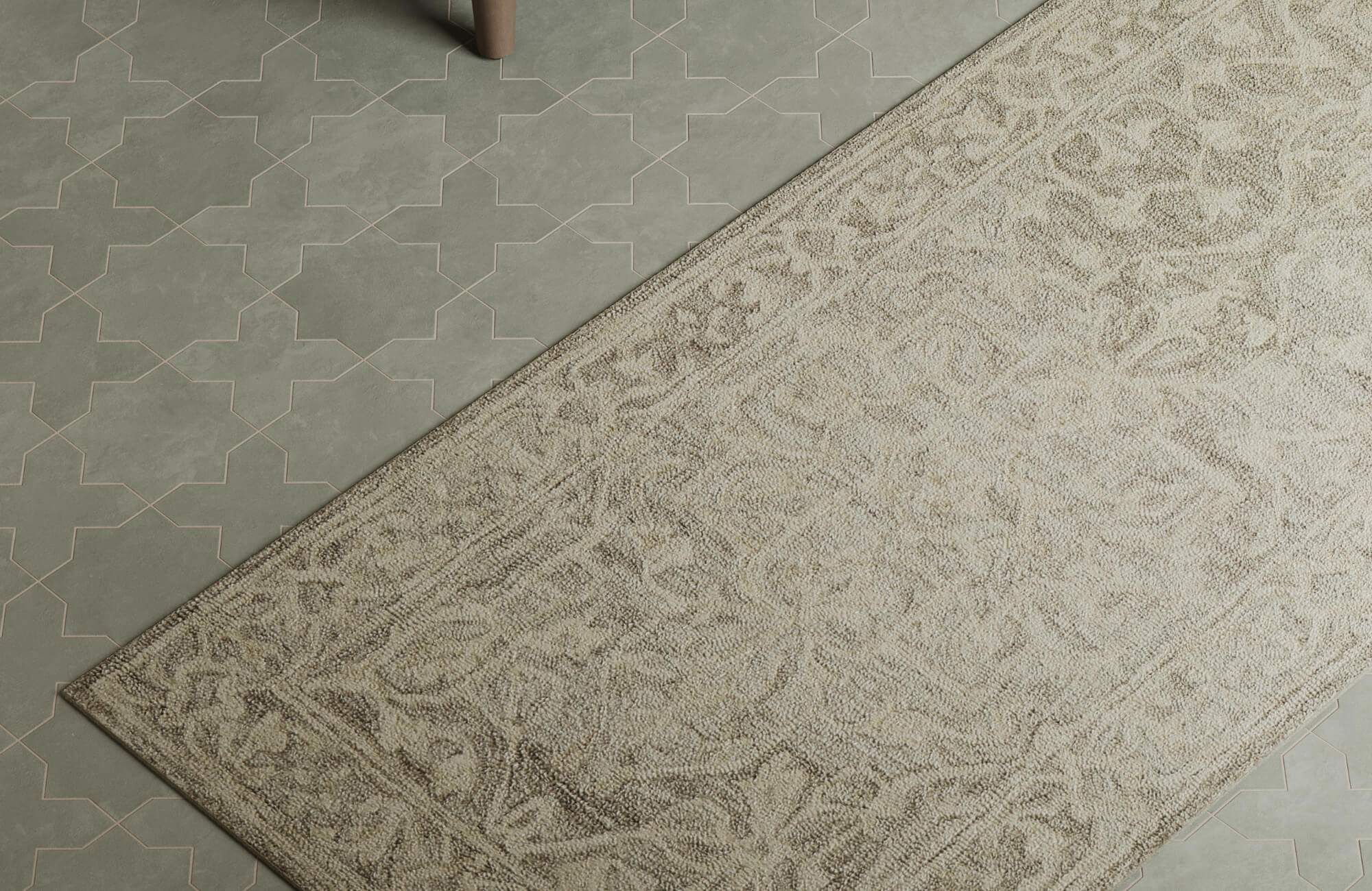 Close-up of a neutral Moroccan rug with intricate floral patterns placed over geometric tile flooring in a modern interior space.