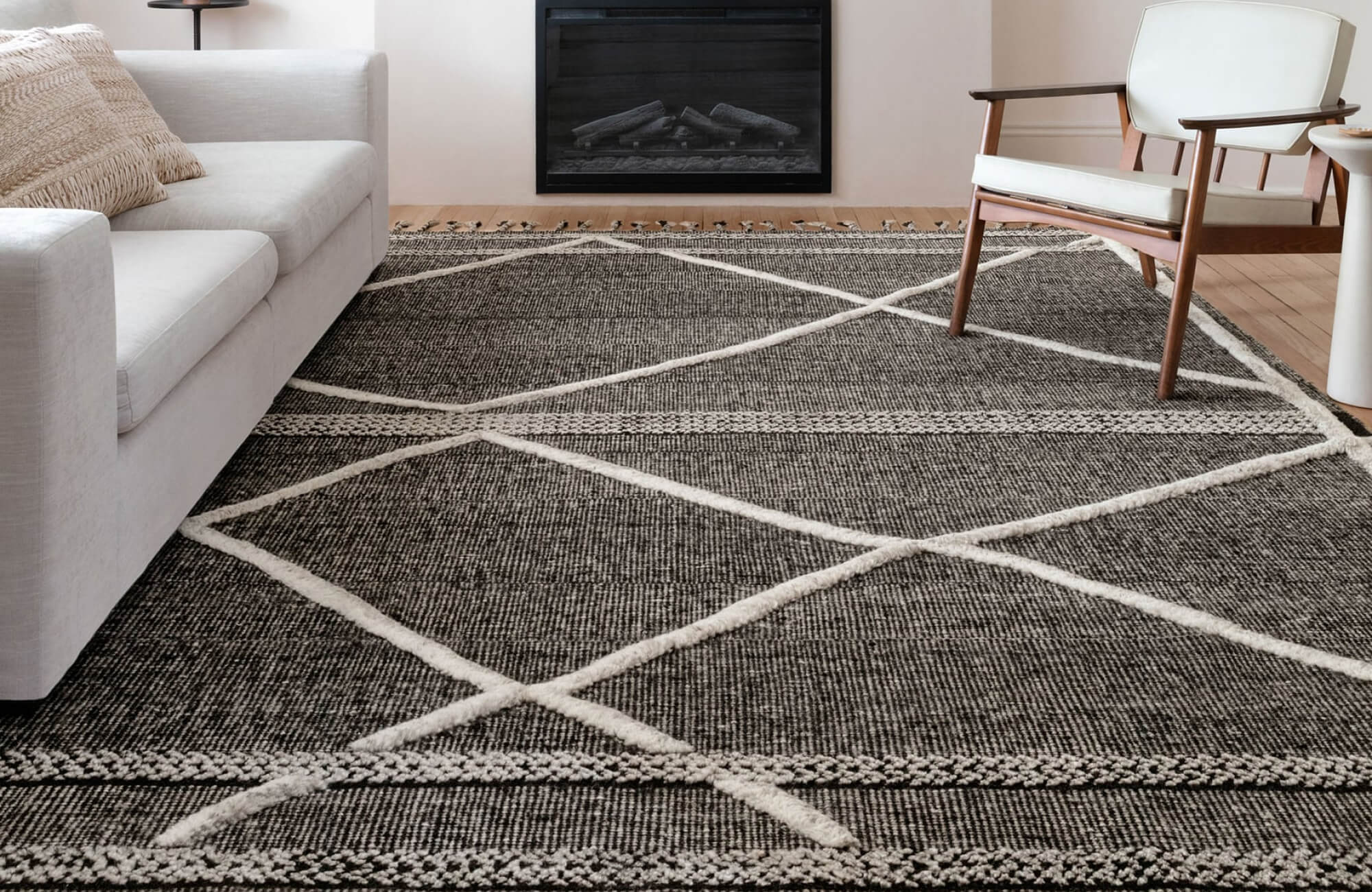 Moroccan-inspired wool rug with ivory diamond pattern on a dark woven background, styled in a minimalist living room.
