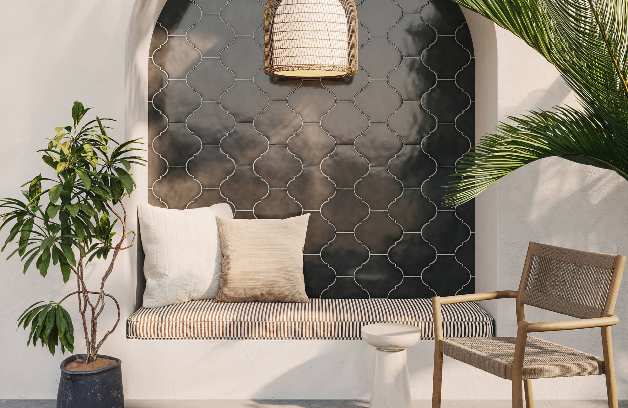 Mediterranean-inspired alcove featuring cushioned bench, textured beige pillows, dark geometric tile backdrop, and potted greenery.