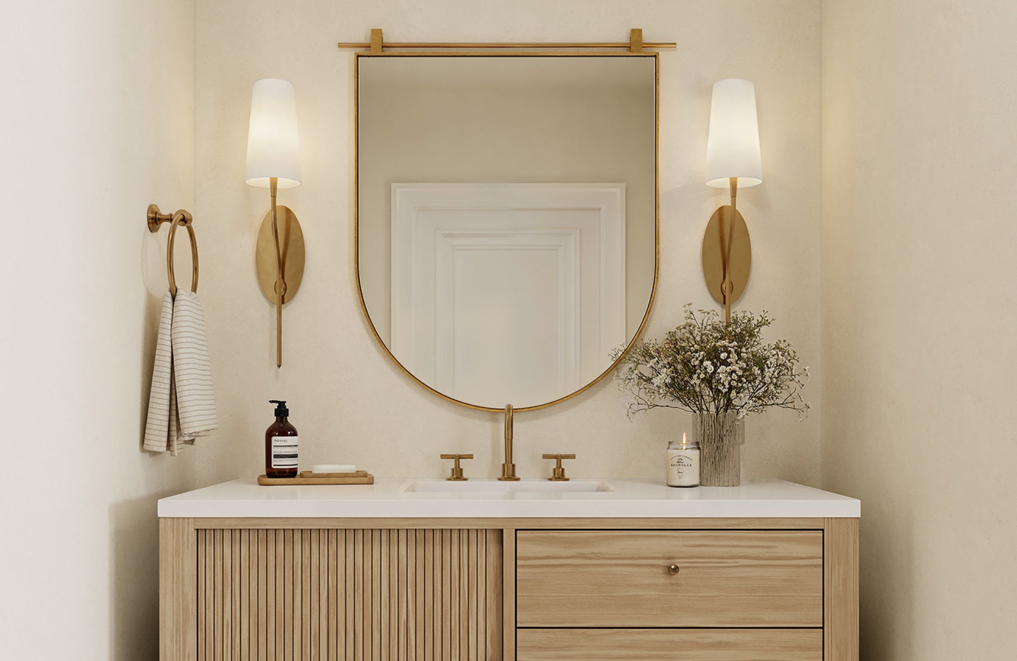 An arched mirror over a 30-inch vanity with brass sconces, highlighting a balanced mirror size and centered placement.