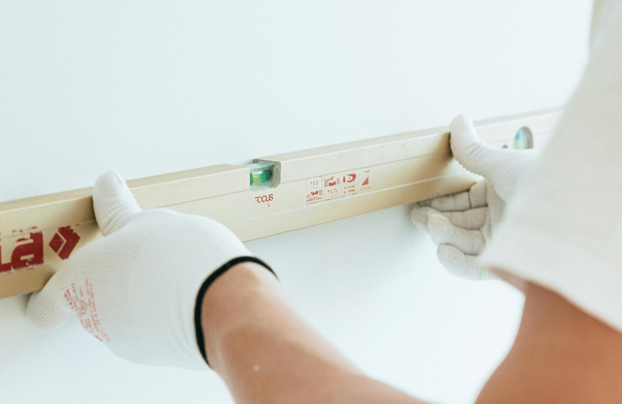 Person measuring wall alignment before installing a mirror above a 30-inch vanity for accurate positioning.