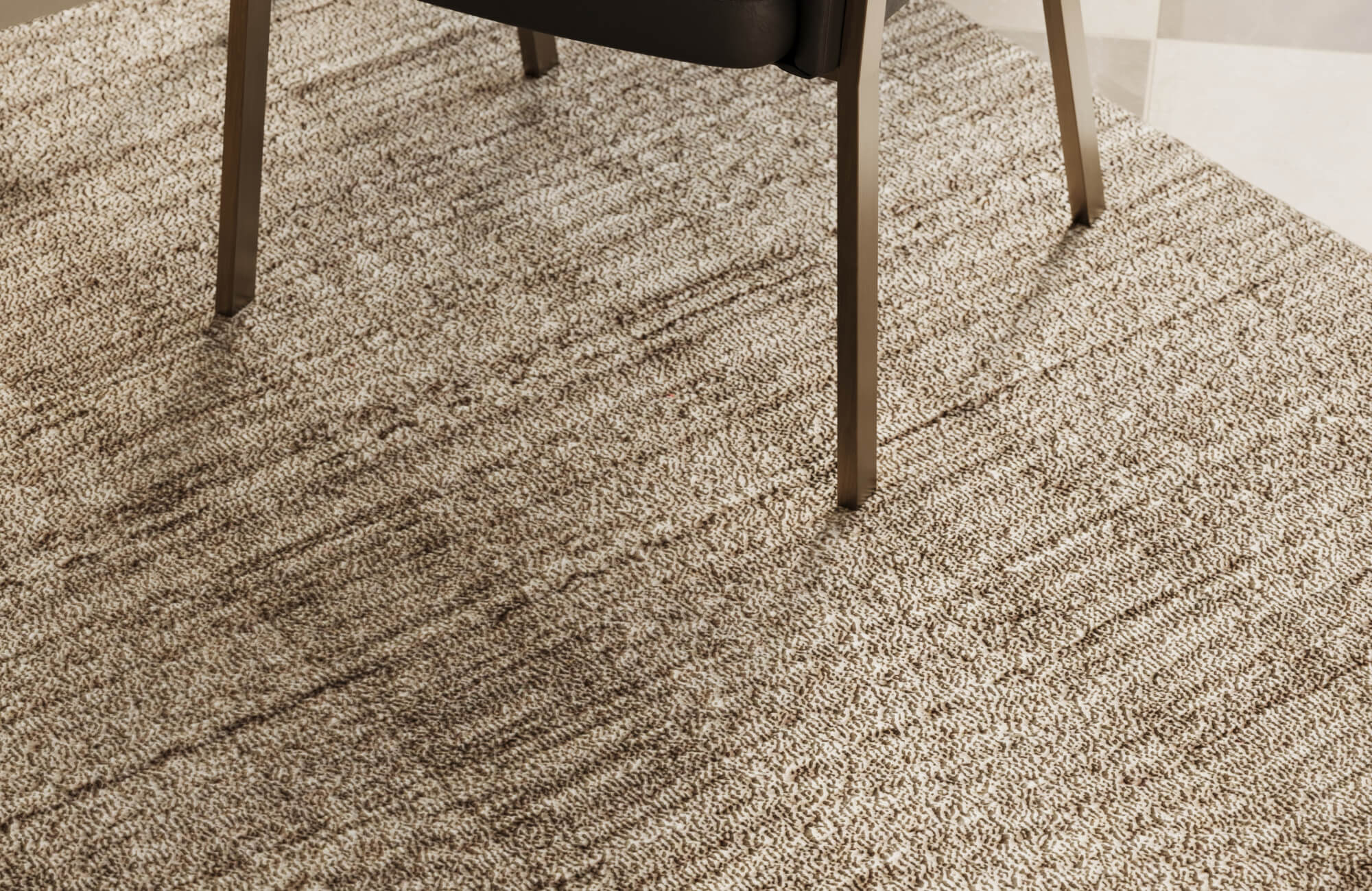 null Textured tan outdoor rug with layered brown striations positioned beneath contemporary chair legs, emphasizing durable weave and natural tone contrast.