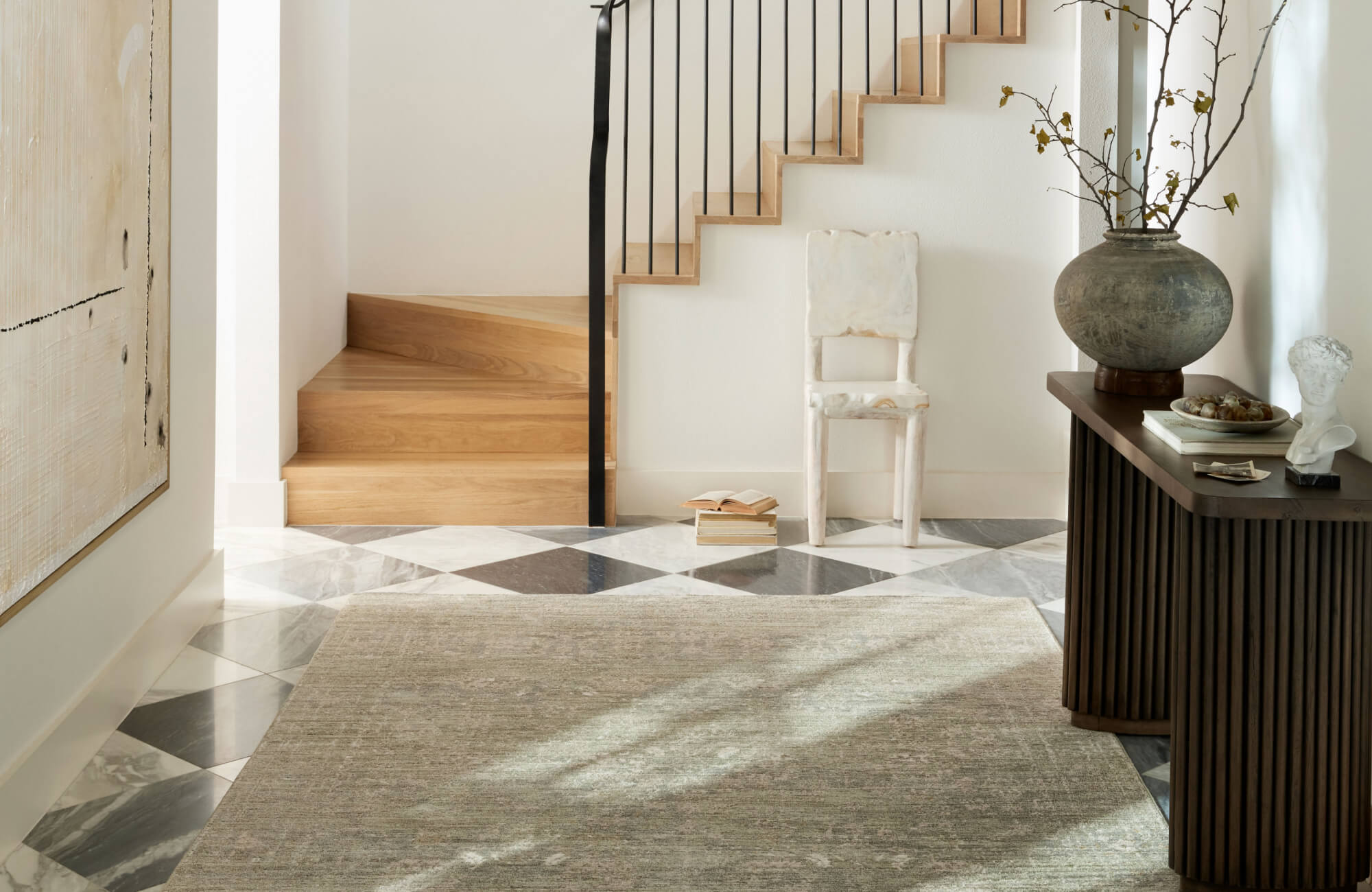 Subtle sage green area rug with a washed, textured finish grounding a modern entryway with marble tile flooring.