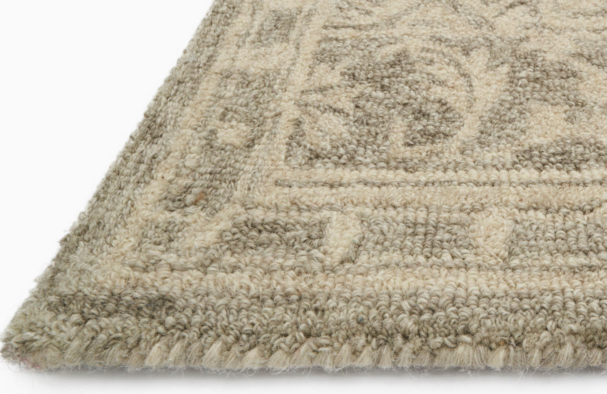 Close-up of a thick, hand-tufted wool rug in beige and taupe tones, showcasing its plush texture and intricate woven pattern.