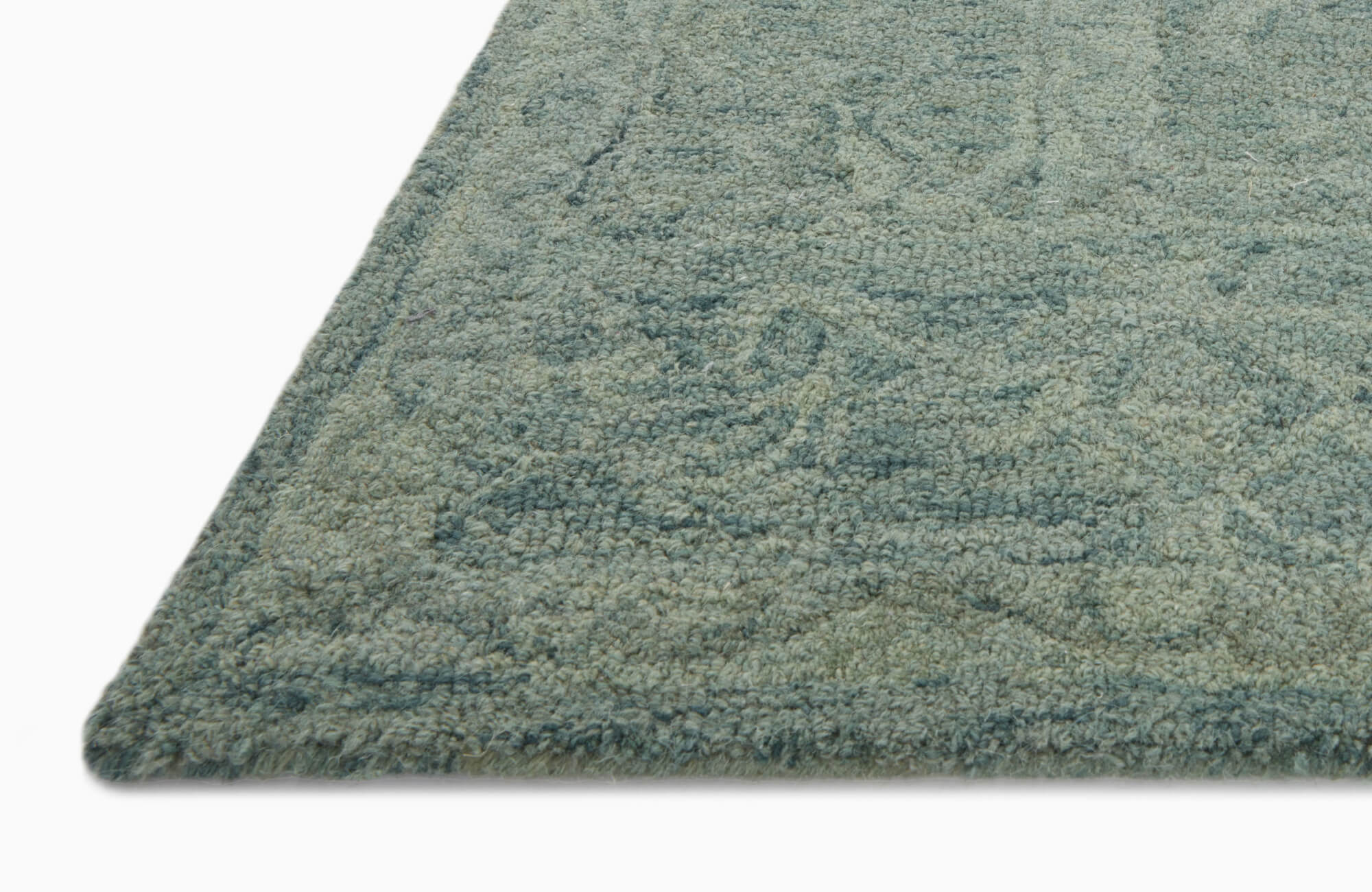 Detailed corner view of a looped pile rug in muted teal tones, featuring soft texture and tonal design.