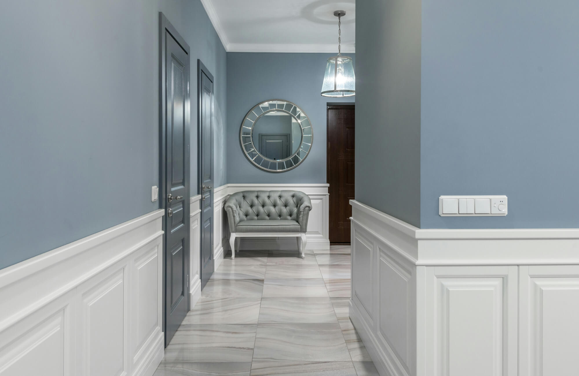 Round mirror with detailed frame in a hallway, creating symmetry and a soft focal point in the entry.