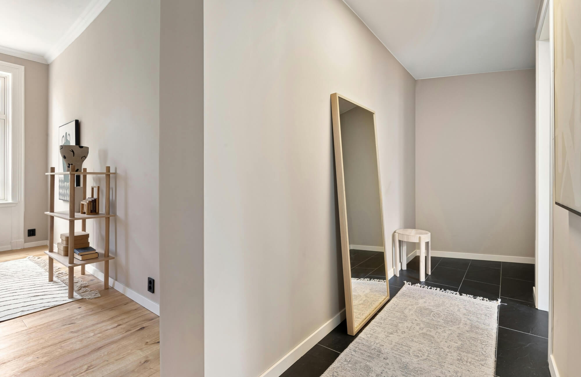 Full-length rectangular mirror leaning against the wall, making a narrow hallway feel taller and more open.