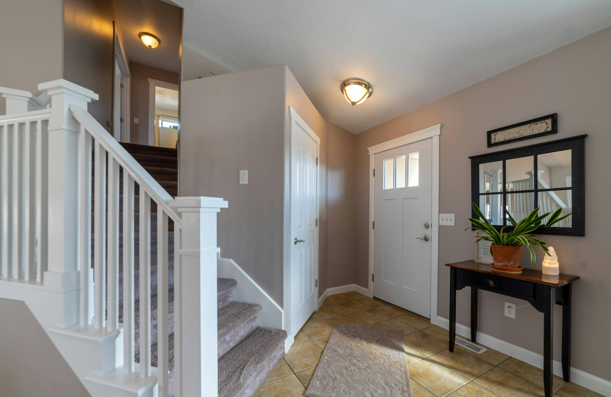 Square mirror with windowpane design above a console, adding structure and reflecting light in the entryway.