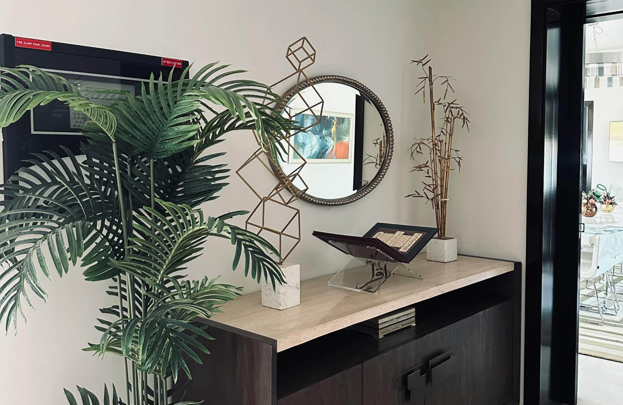 Round mirror above a console with greenery, softening the layout and balancing modern entry decor.