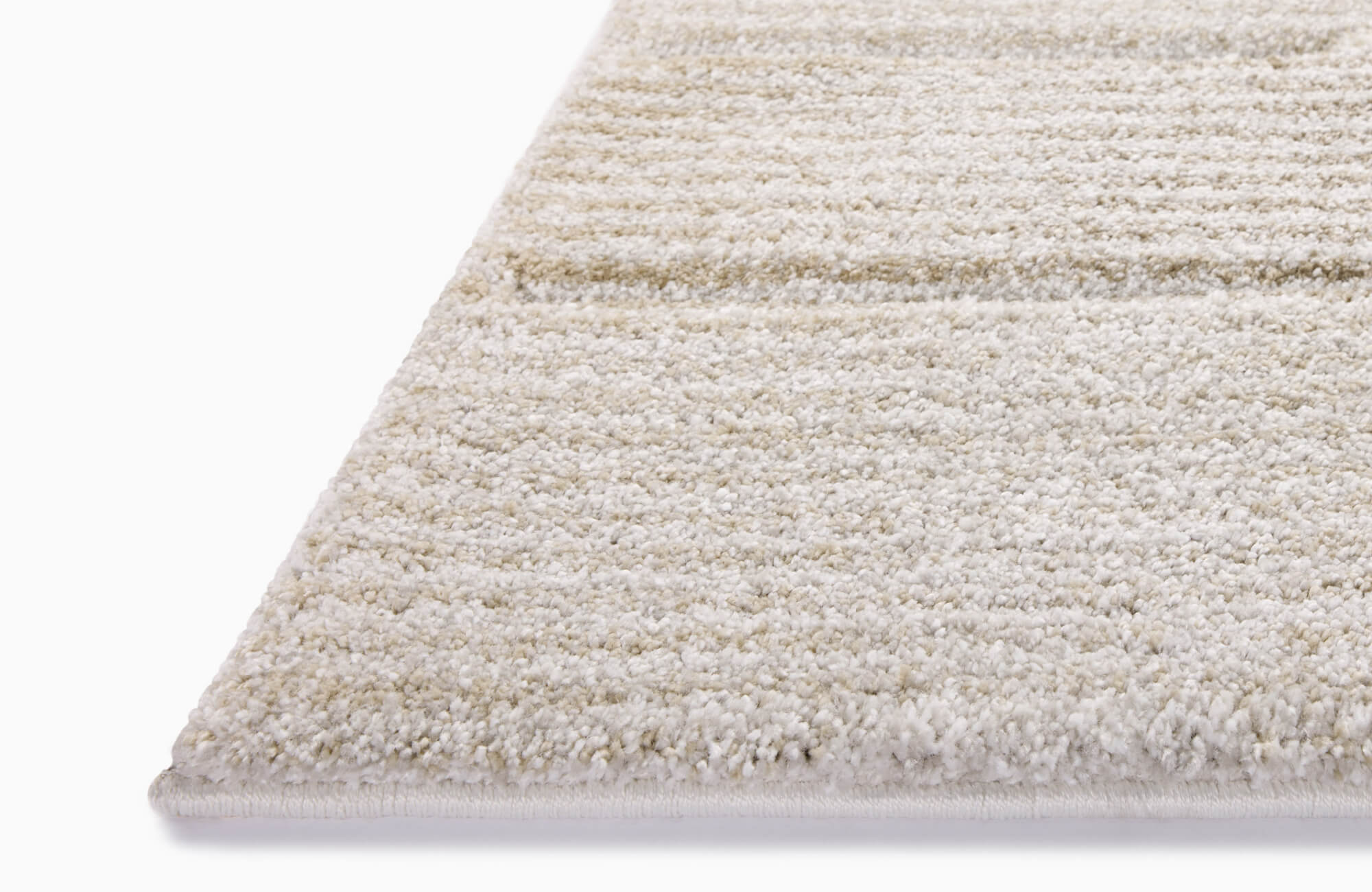 null Low-angle close-up of a cream-colored polypropylene rug with a plush, subtly striped texture and neatly bound edge.
