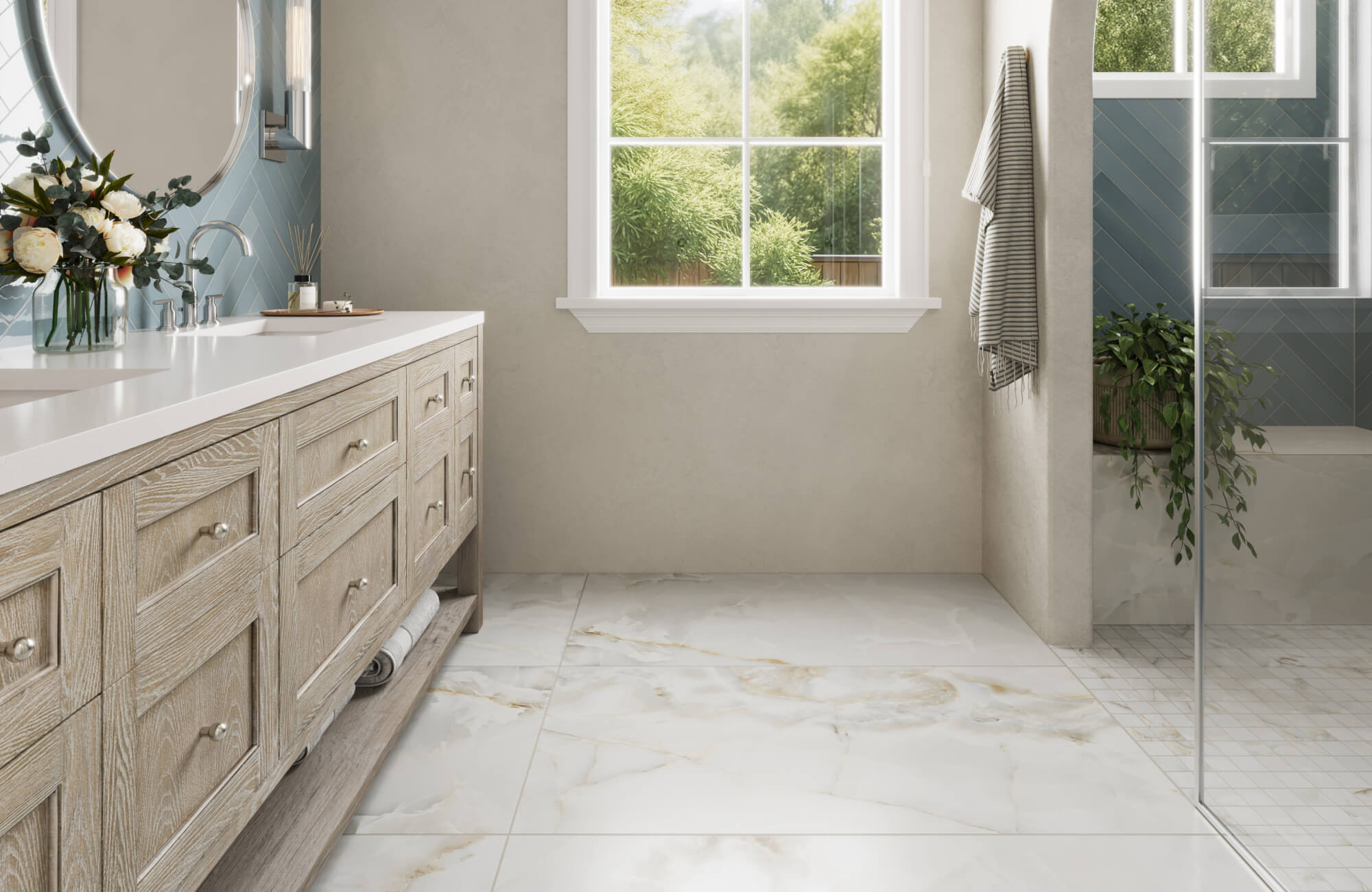 Bright bathroom with large marble-look floor tiles, pale wood vanity, blue shower tile, and glass enclosure.